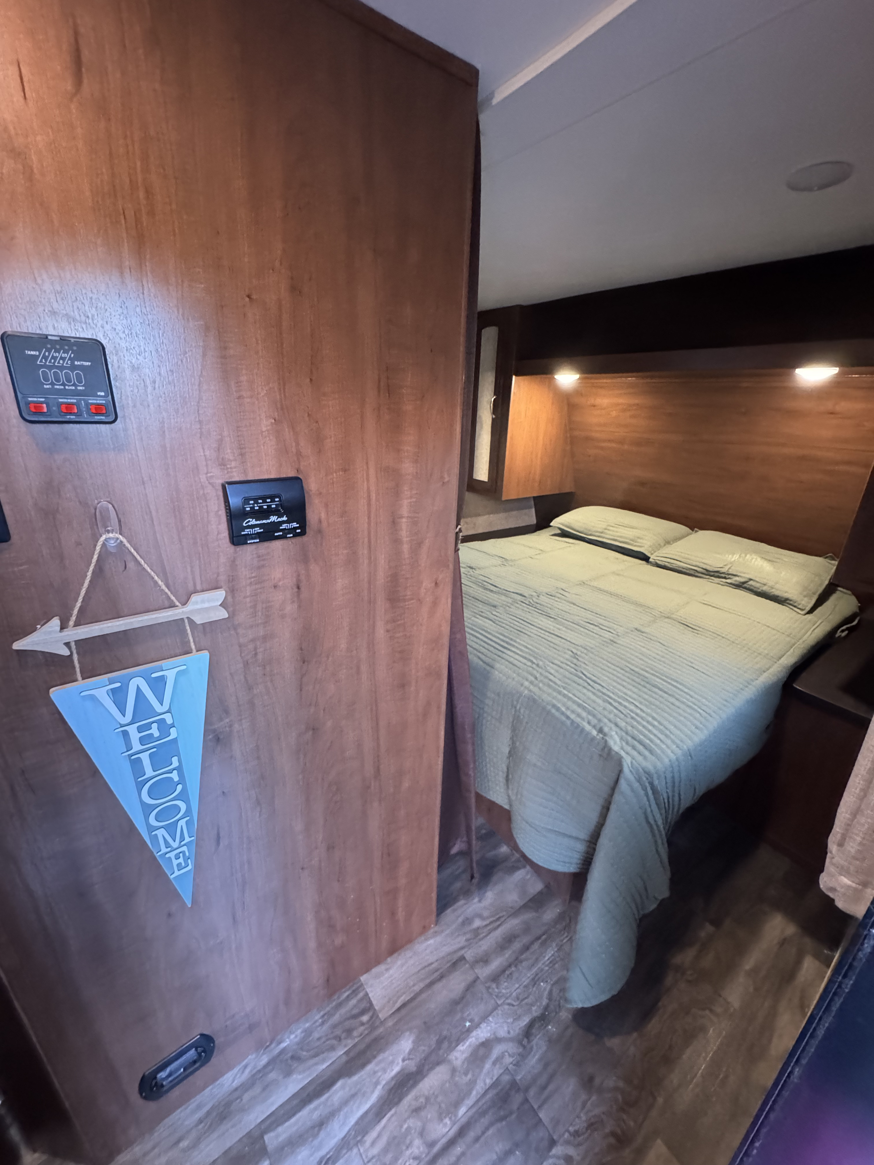Cozy RV rental bedroom with comfort controls and a welcome sign, featuring wood finishes and a comfy bed for travel adventures.. Jayco Jay Feather 2017