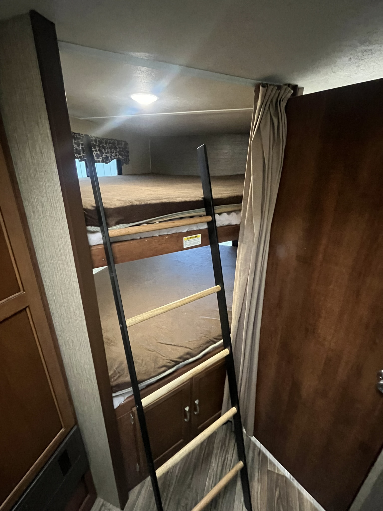 Inside this RV rental, comfortable bunk beds are accessible via a sturdy ladder, offering a compact sleeping area with storage below.. Keystone RV Passport Grand Touring 2017