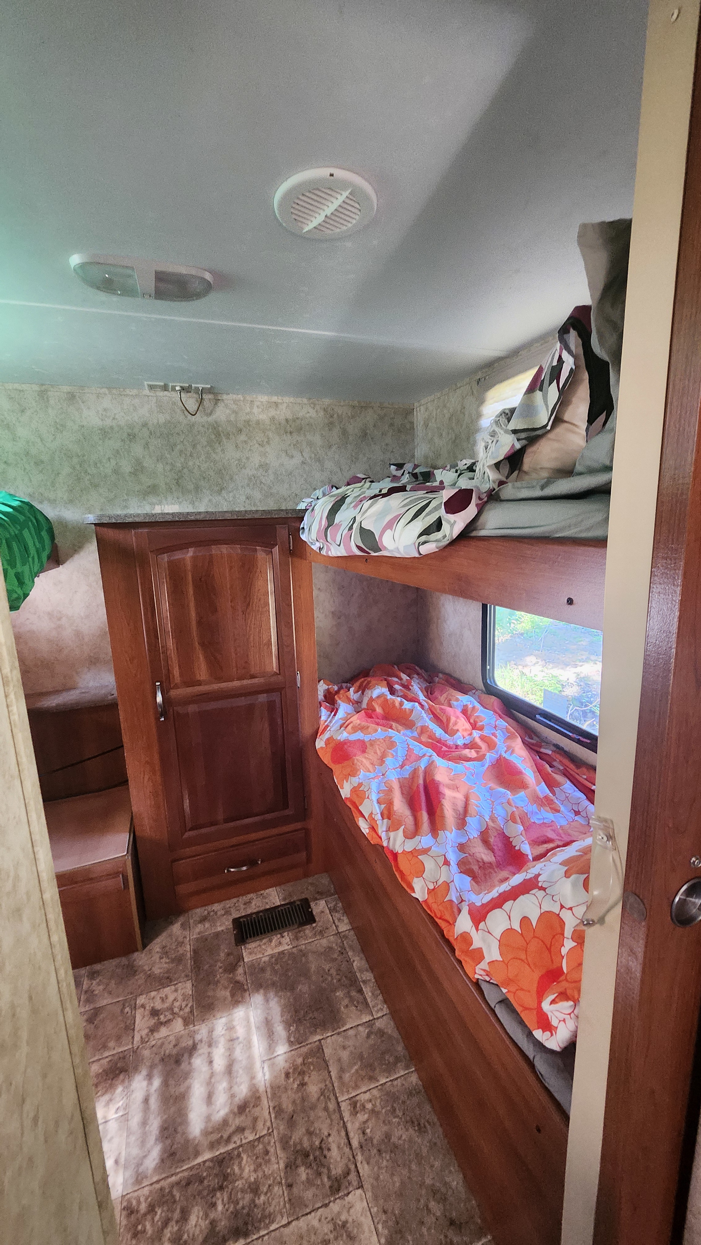 Inside an RV rental: cozy bunk beds with colorful bedding, a small closet, and tiled floor, optimized for small spaces.. Keystone RV Cougar 2011