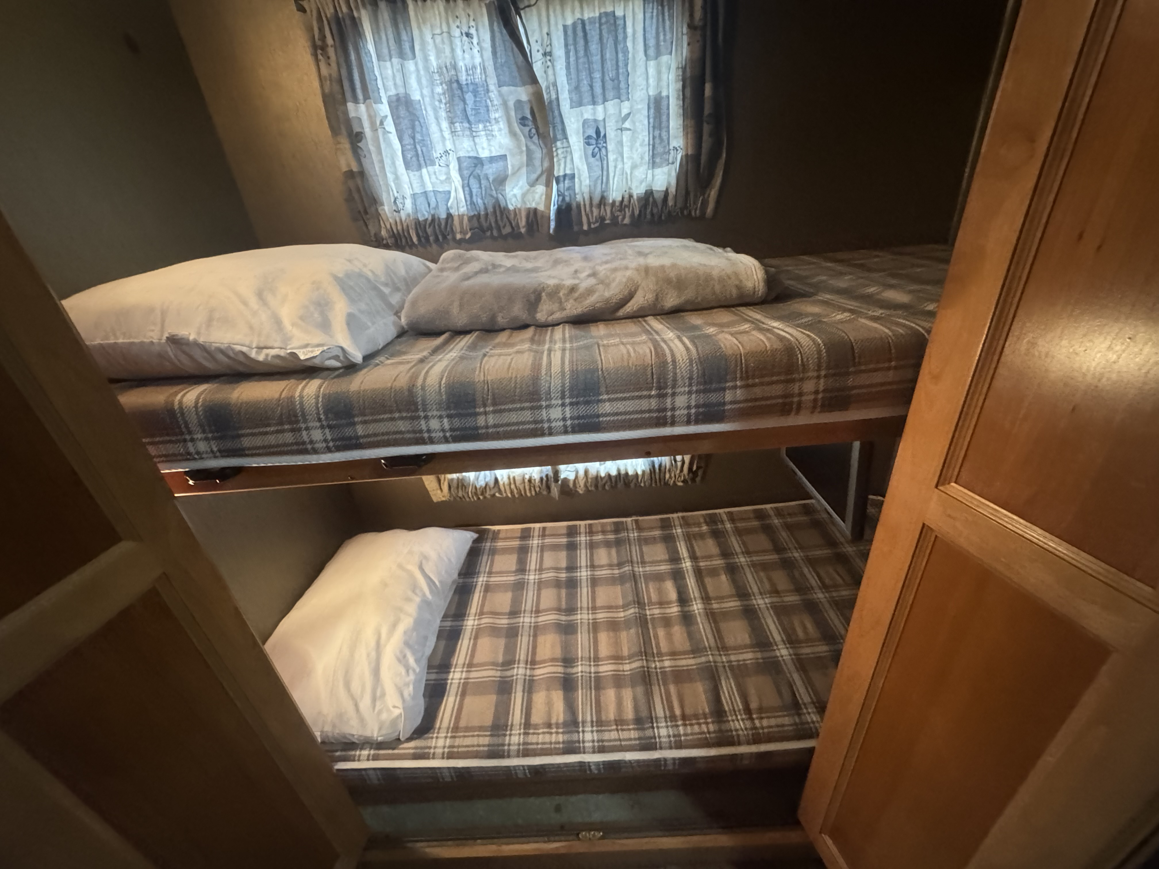 Cozy RV rental bunk beds feature plaid bedding and pillows, ideal for family sleeping in this travel trailer.. Tiffin Allegro 2013
