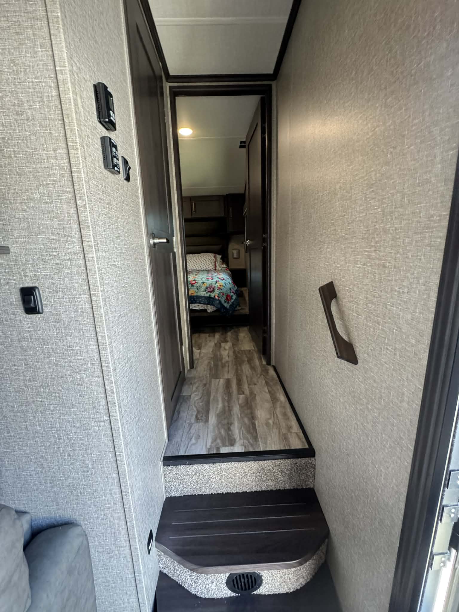 Interior rv rental view: A hallway with steps leading to a bedroom, showing wall controls and a grab handle.. Grand Design Reflection 2022