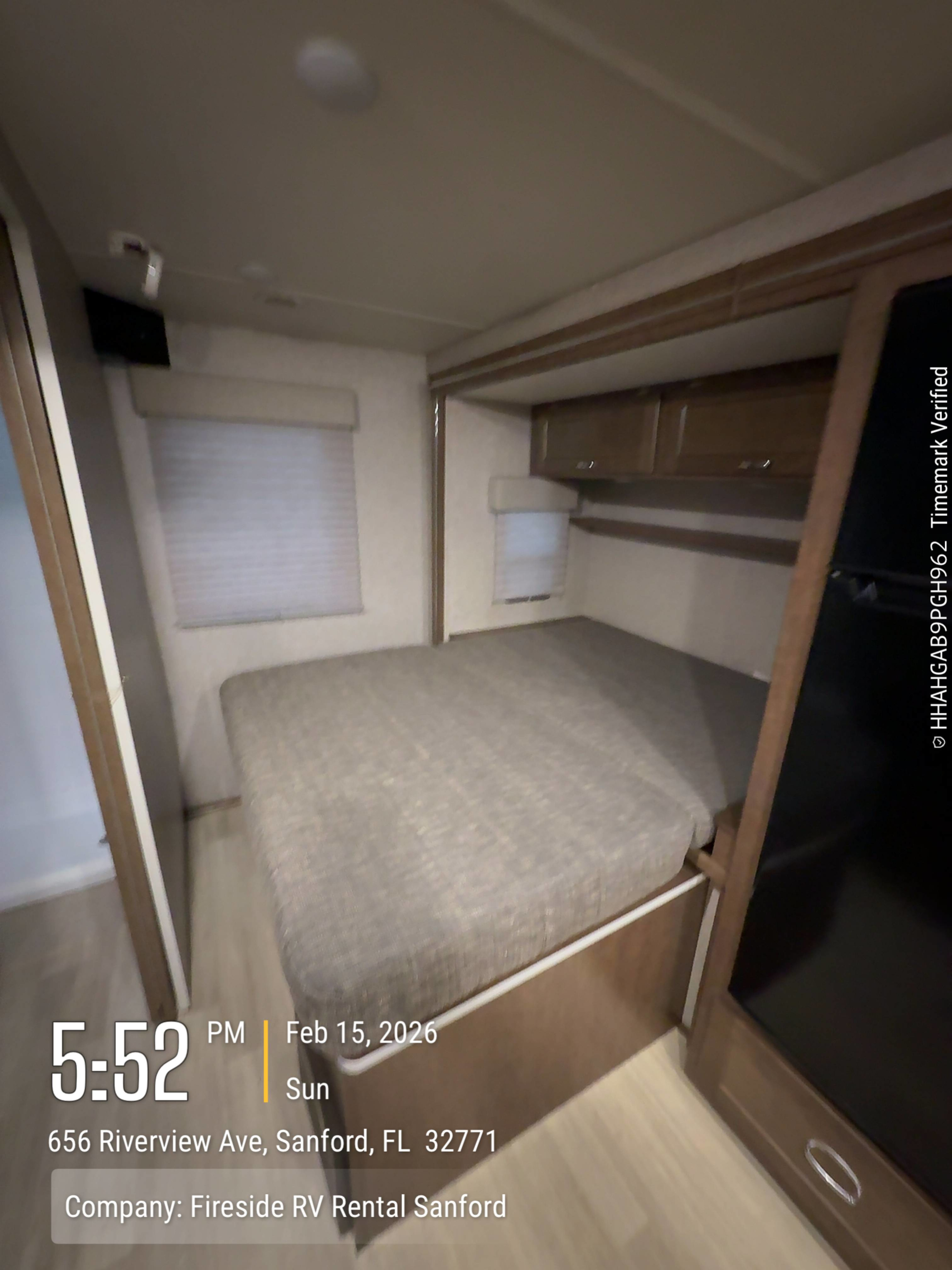 Interior view of an RV rental bedroom with a large bed, windows, and overhead storage, from Fireside RV Rental Sanford.. Winnebago Porto 2020