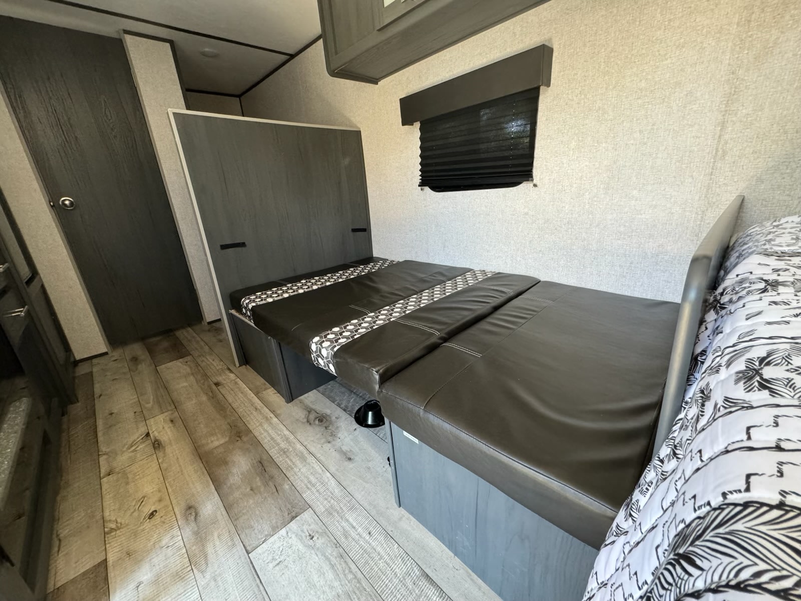 RV rental interior features a convertible bed/dinette with dark cushions, wood-look flooring, and a window blind for your trip.. Aspen Trail Aspen Trail Trailer 2022