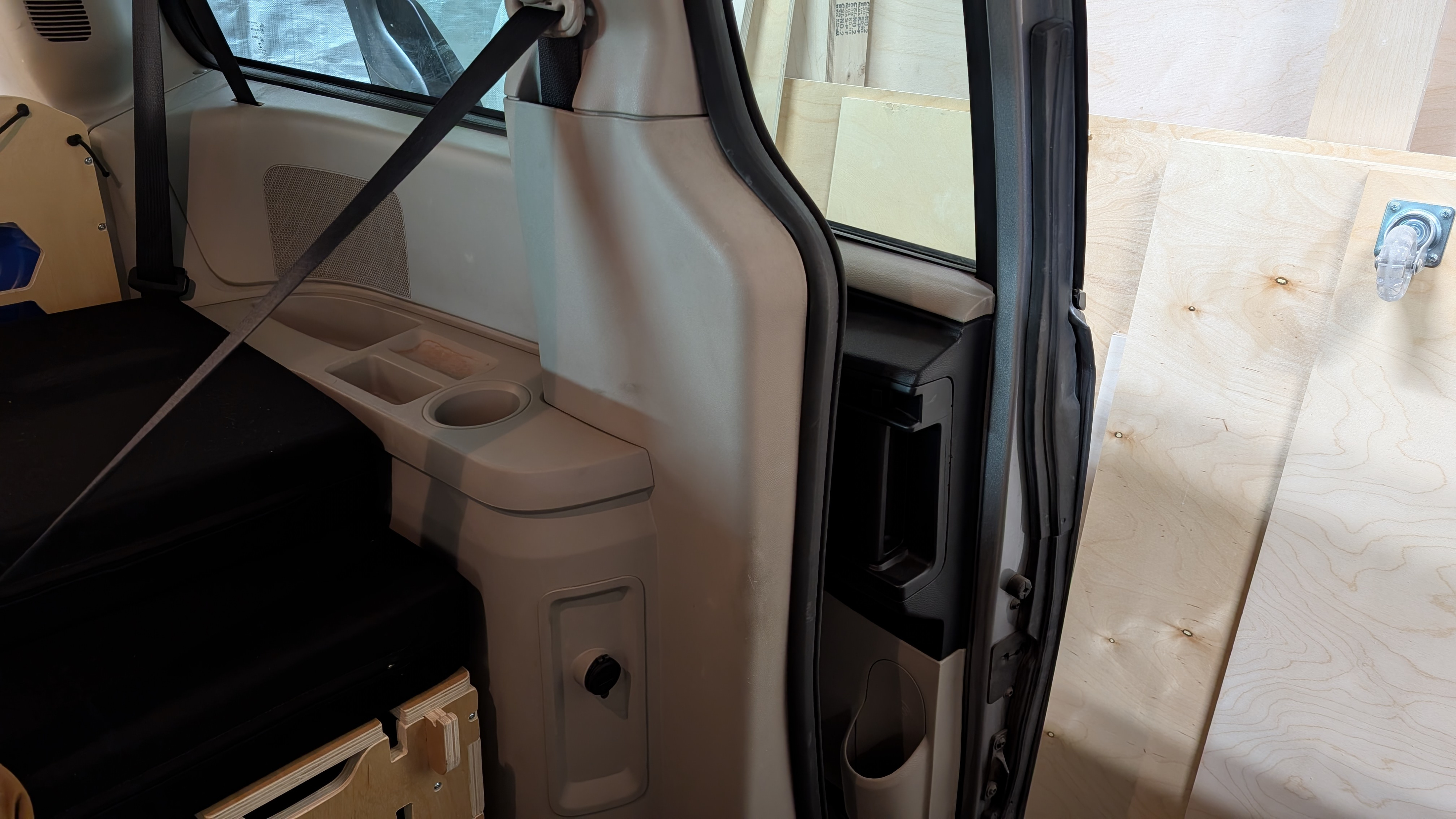 Inside an RV rental van: custom bed, storage unit, cup holders, and a power outlet for travel.. Dodge Grand Caravan 2016