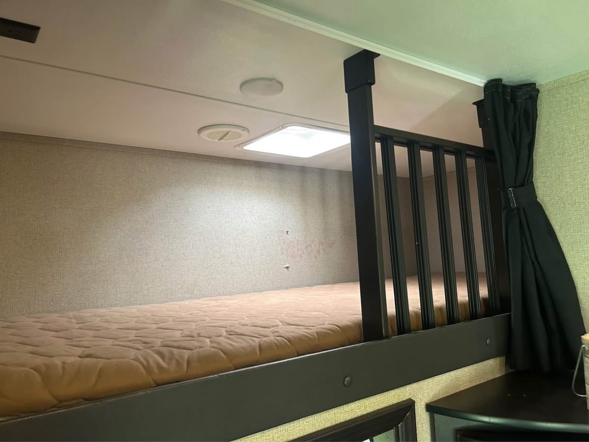RV rental interior featuring bunk beds with a dark safety railing, soft mattress, and overhead lights for comfort.. Keystone RV Carbon Toy Hauler 2018