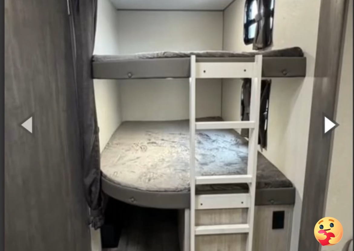 Inside this RV rental, comfortable bunk beds feature gray bedding, a white ladder, and small windows for sleeping.. Coachmen Explore 2026 273DBHCK 2026