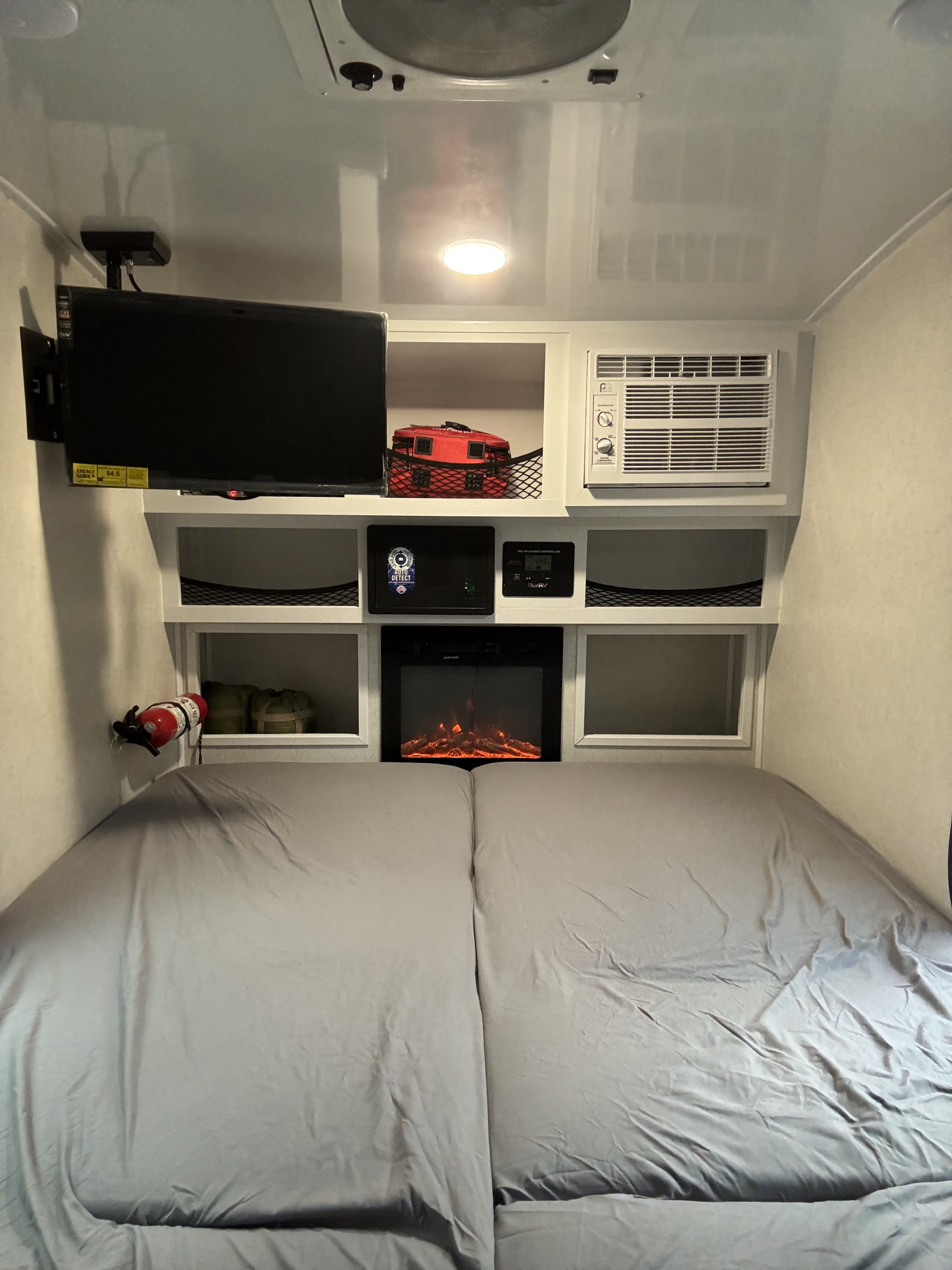 Cozy RV rental bedroom featuring a TV, AC, electric fireplace, and storage for compact travel comfort.. ModernBuggyRV 12LKR 2026
