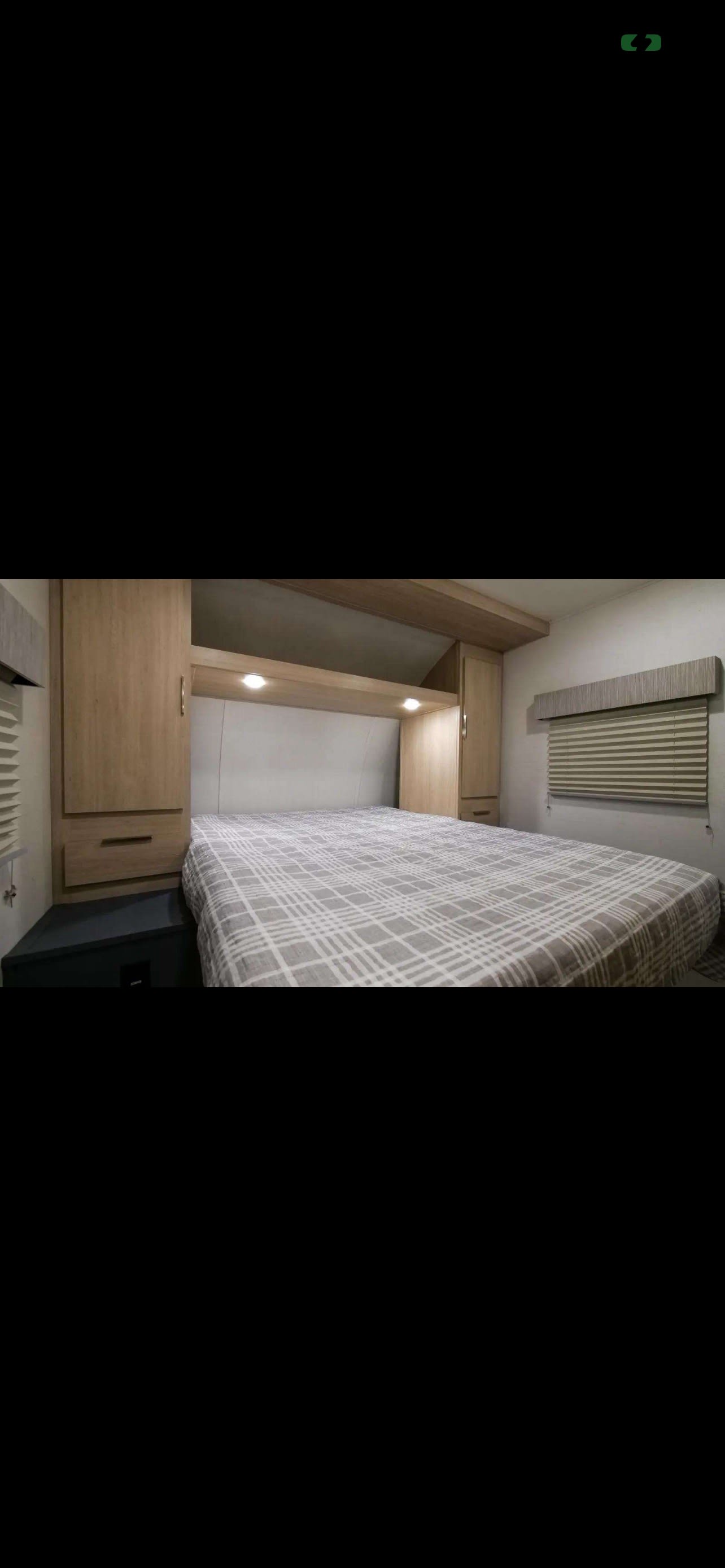 Comfortable RV rental bedroom featuring a plaid bed, overhead storage, and window blinds for a cozy stay.. Forest River Tracer 2024