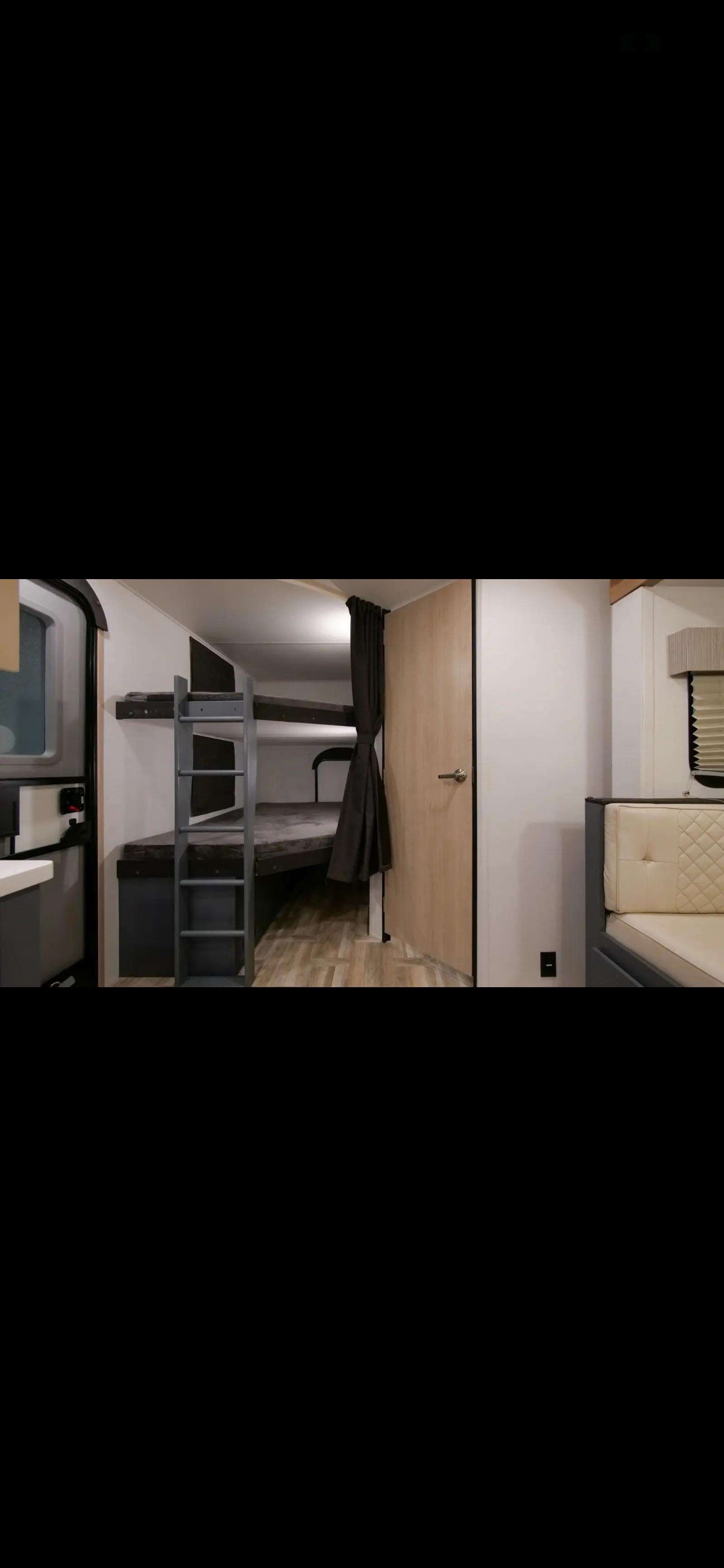 **RV rental** interior: compact design with bunk beds, a ladder, door, and a comfortable quilted bench seat.. Forest River Tracer 2024
