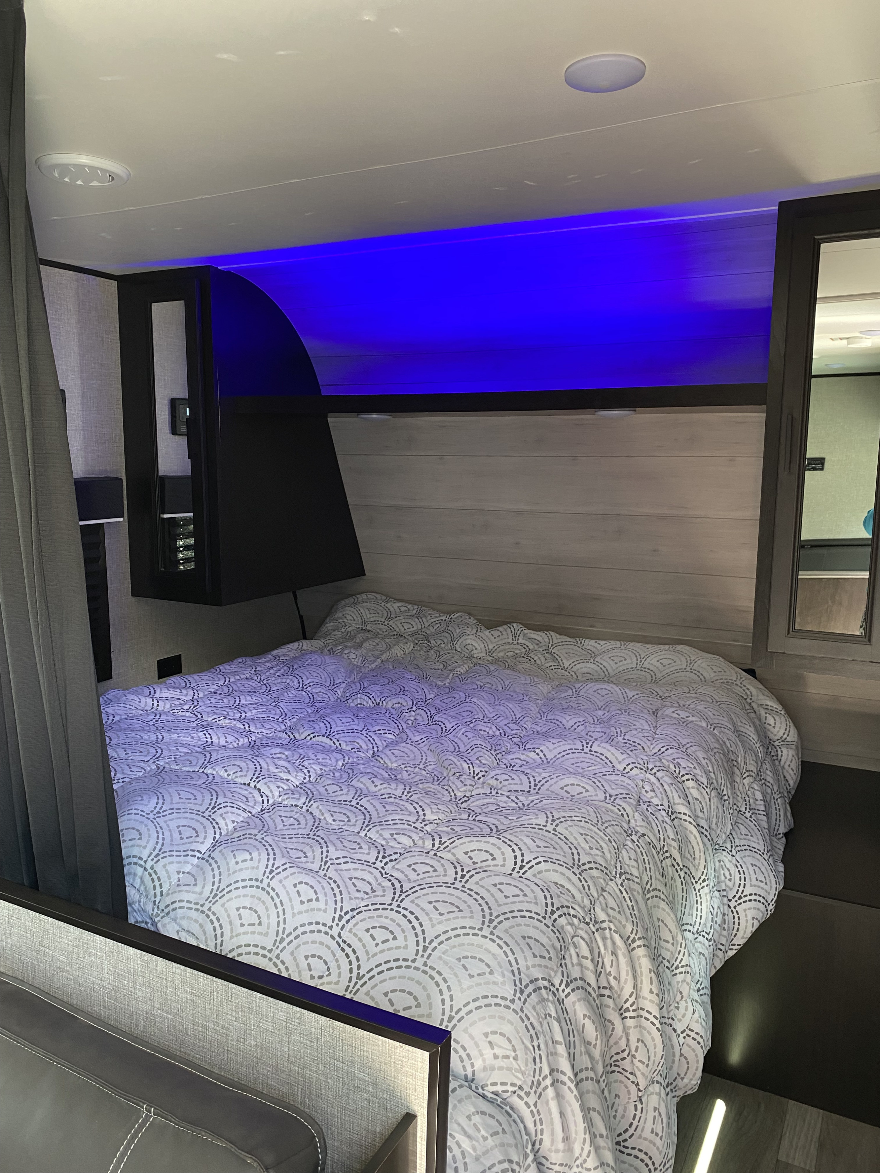 Modern RV rental bedroom featuring a patterned bed, vibrant blue accent lighting, and overhead fixtures.. Jayco Jay Flight SLX Rocky Mountain Edition 2022