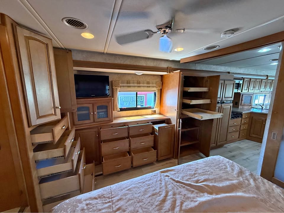 Spacious RV rental interior with numerous open wooden cabinets, drawers, TV, and bed. Perfect for your travel adventures.. Winnebago Adventurer 2012