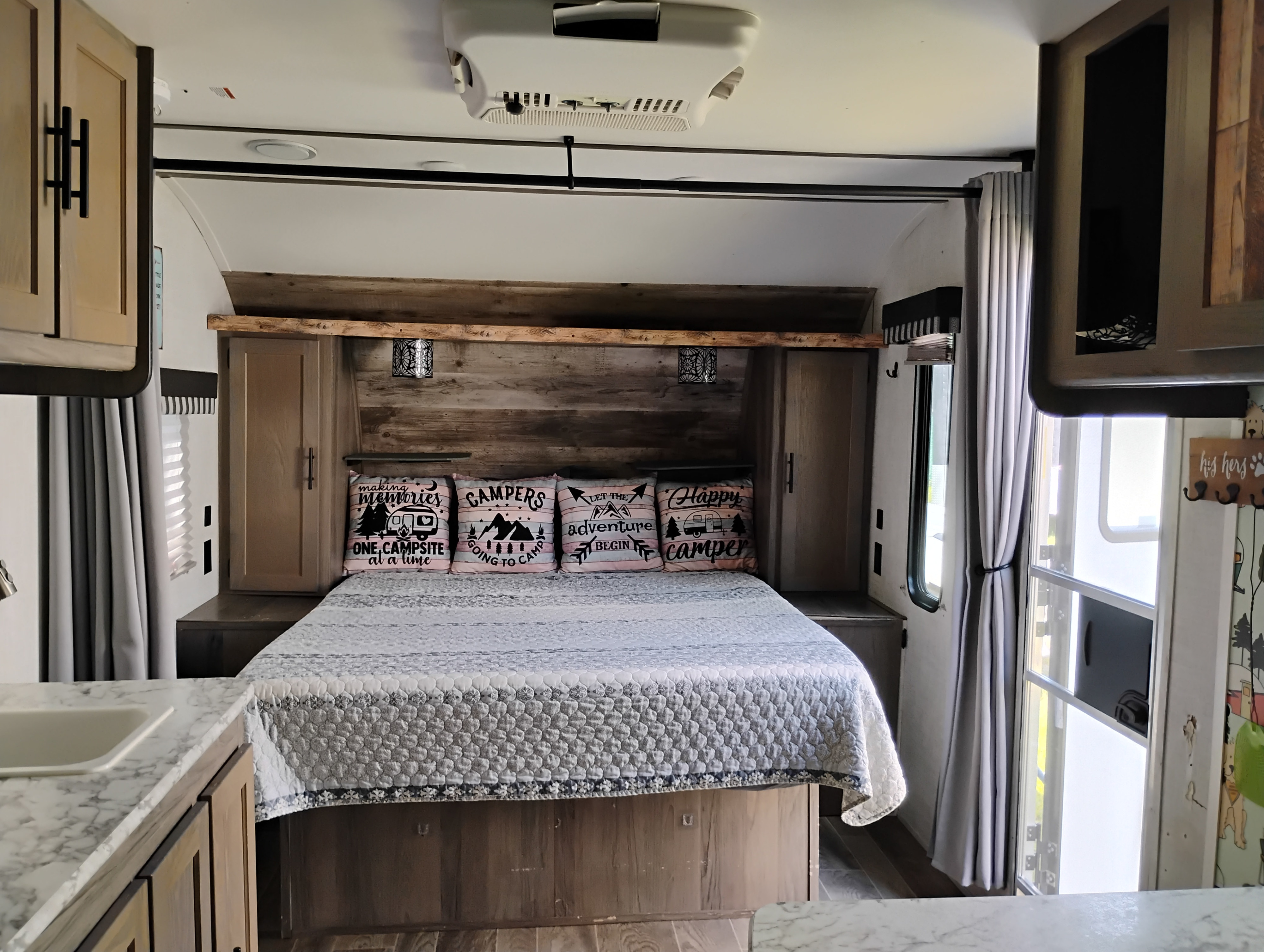Cozy RV rental bedroom featuring a comfortable bed with fun camping-themed pillows, wood accents, and built-in storage.. Gulf Stream Ameri-Lite Super Lite 2021