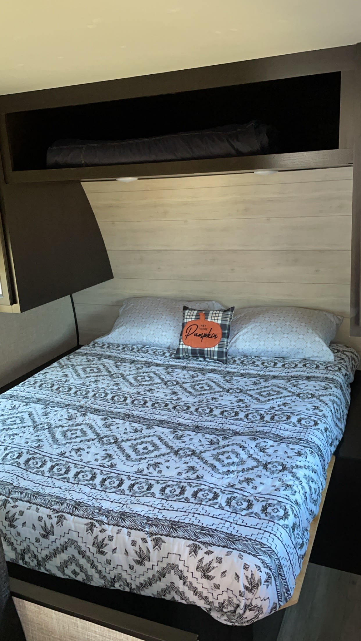 Cozy RV rental bedroom with a comfortable bed, patterned comforter, pumpkin pillow, and convenient overhead storage.. Jayco Jay Flight 2023