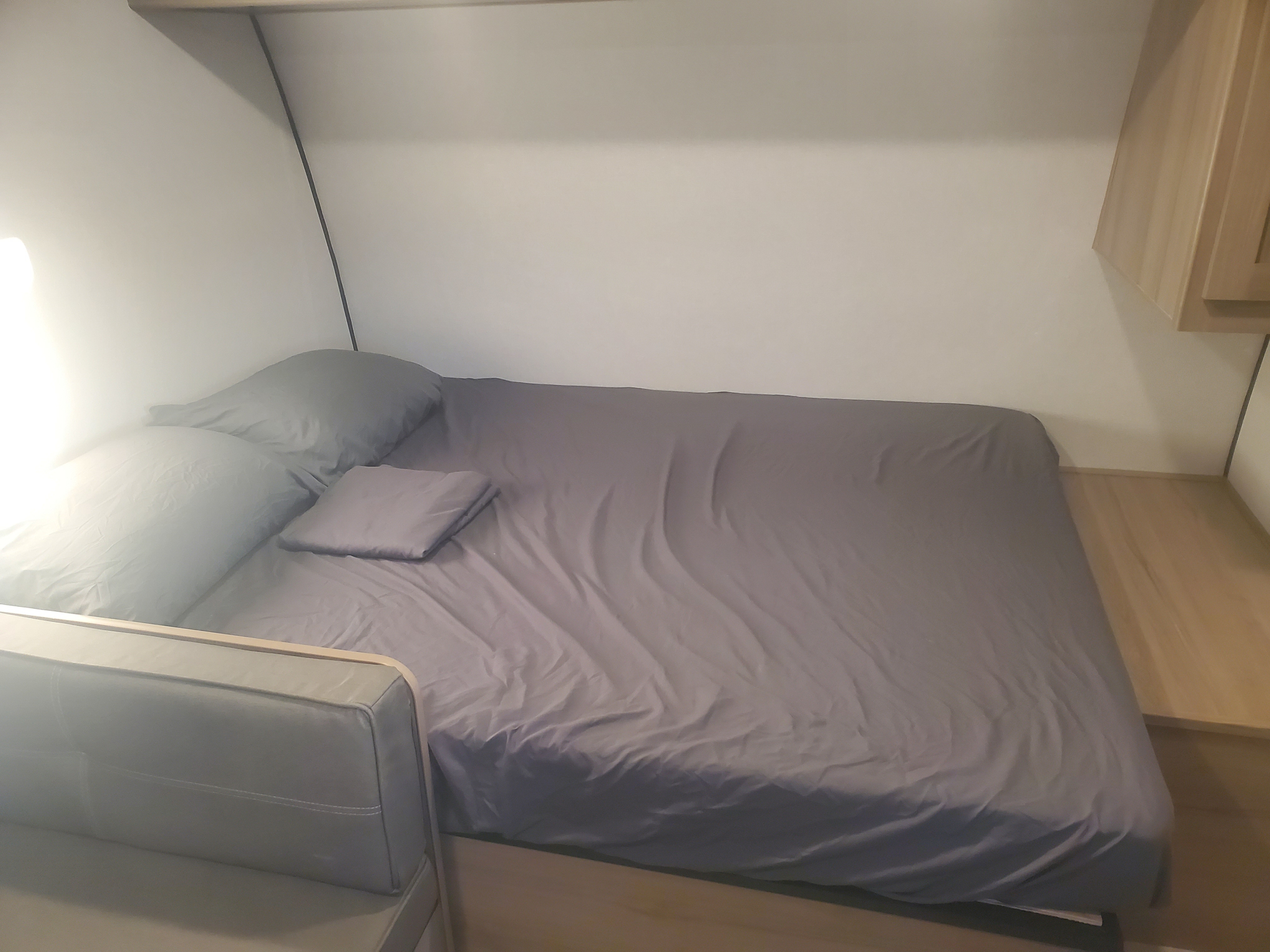 RV rental interior: A cozy sleeping area with a grey bed, pillows, and bright ambient light, perfect for your journey.. Keystone Coleman 2026