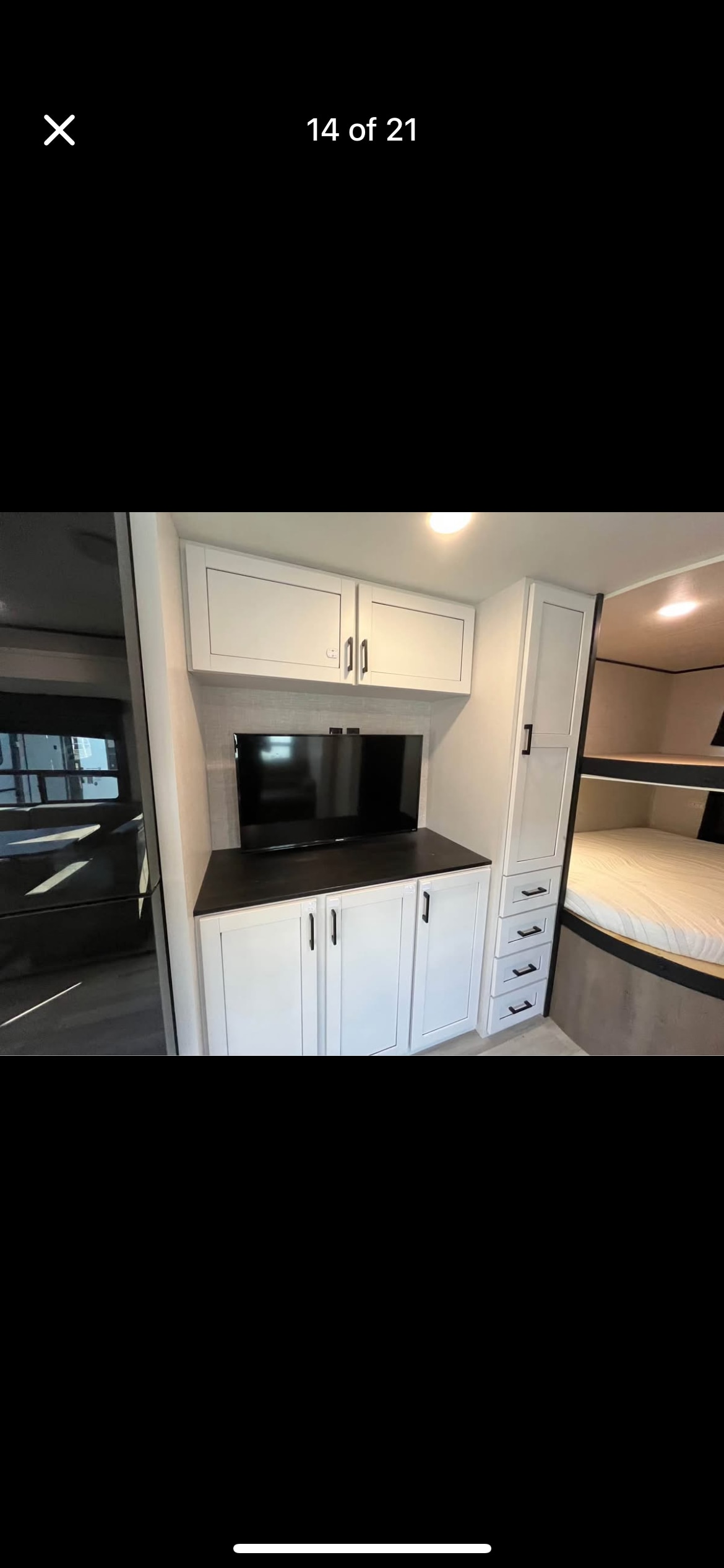 RV rental interior: modern entertainment unit with TV, white storage cabinets, and bunk beds for guests.. Highland Ridge RV Open Range 2025