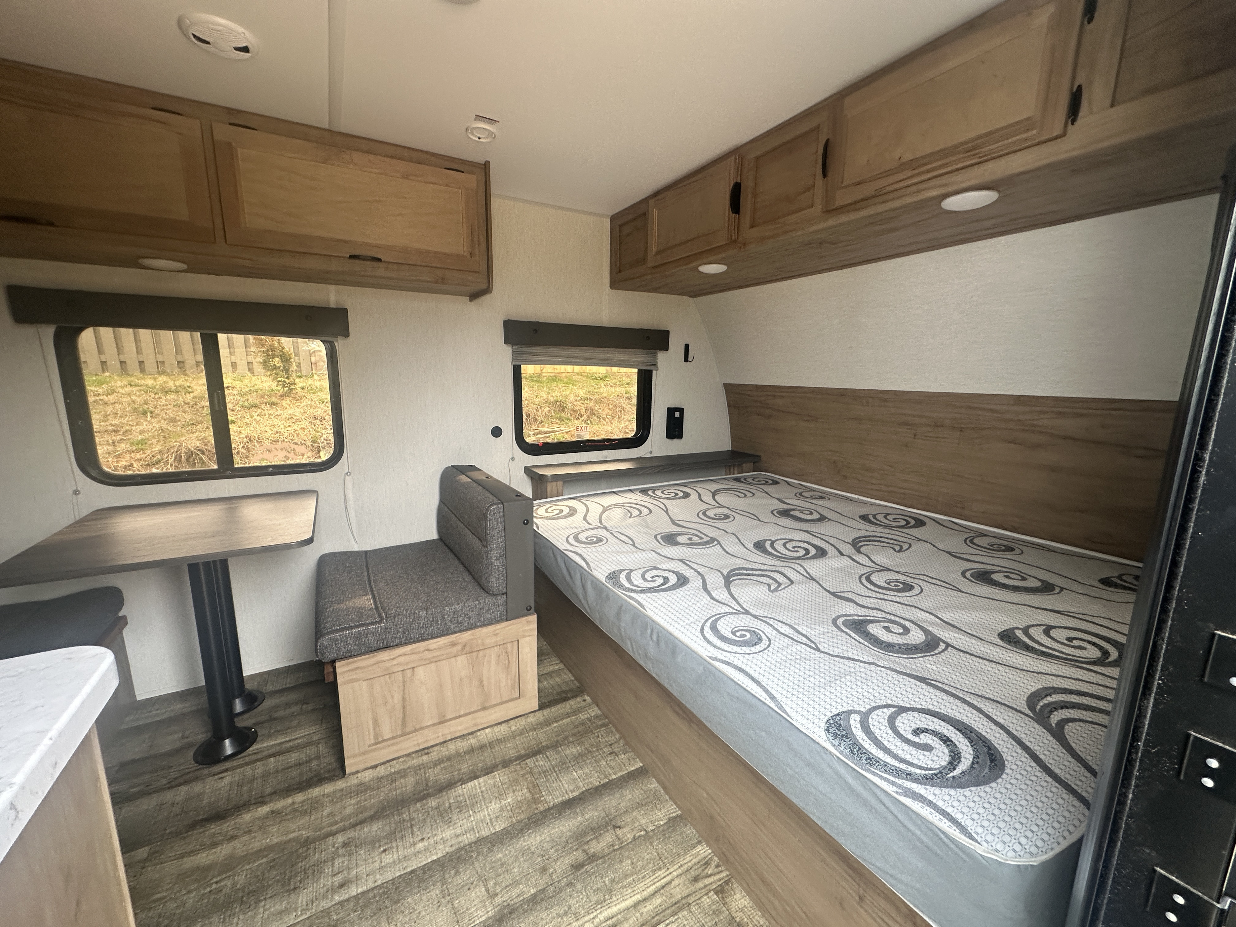 Cozy rv rental interior with a comfortable bed, dinette seating, overhead cabinets, and windows for scenic views.. Forest River Cherokee Wolf Pup 2024