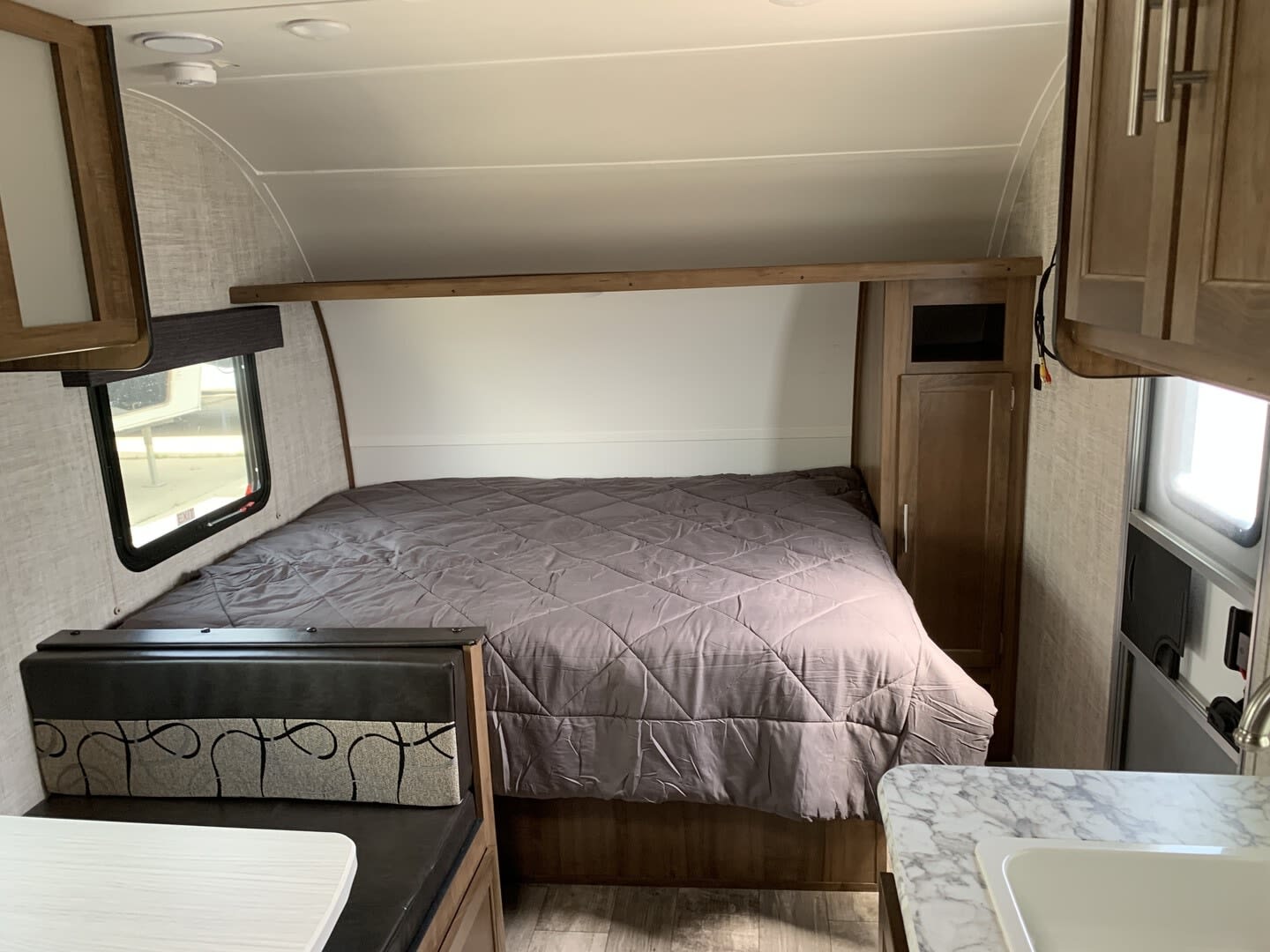 rv rental: Interior view with a grey comforter on the bed, nearby dinette seat, and glimpse of the kitchen sink.. Gulf Stream Ameri-Lite Super Lite 2022