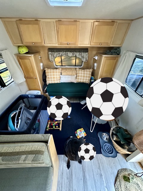 Cozy RV rental interior: bed, overhead cabinets, a baby's crib, and a pet dog on the floor. A compact, family-friendly living space.. R-Vision Trail-Lite 2005