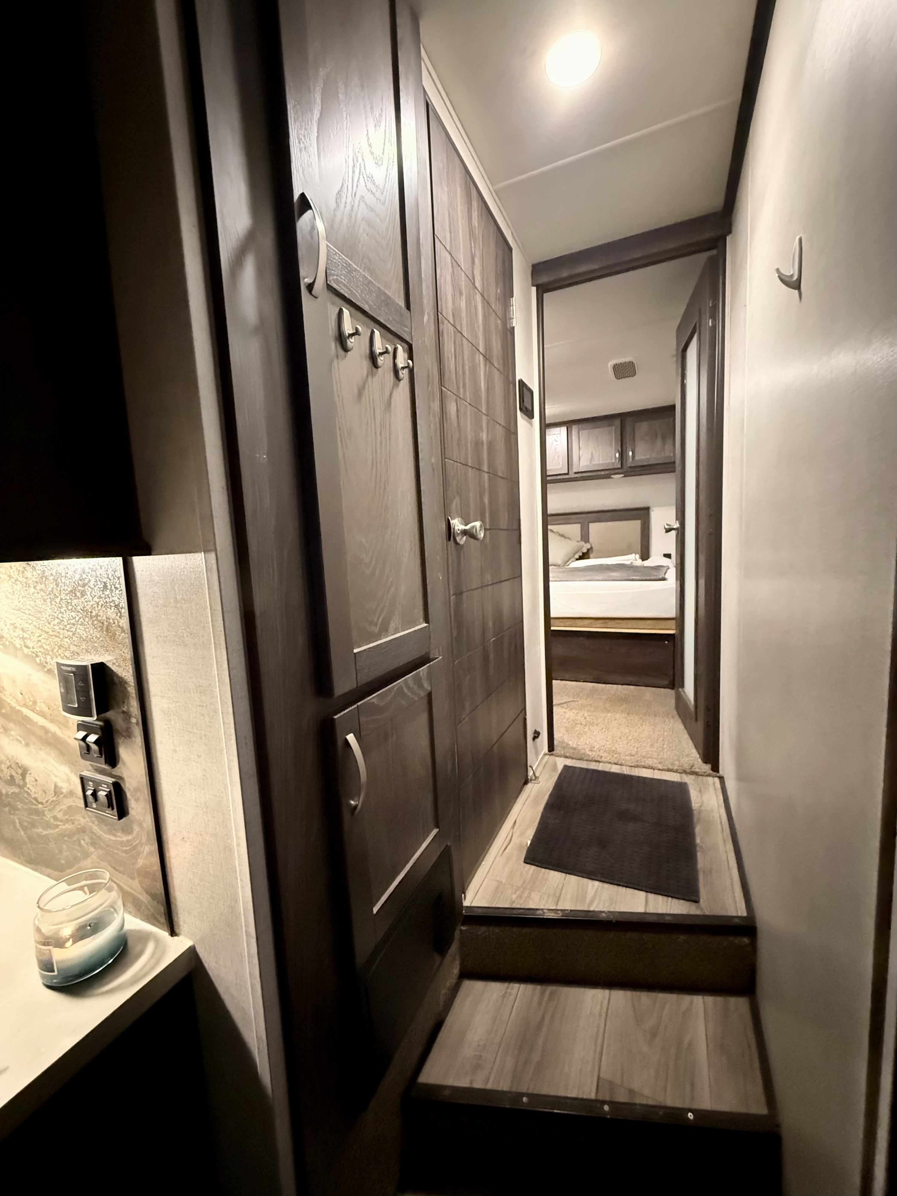 Modern RV rental interior, showing a hallway with a candlelit counter, controls, and steps leading to the bedroom.. Highland Ridge RV Open Range 2021