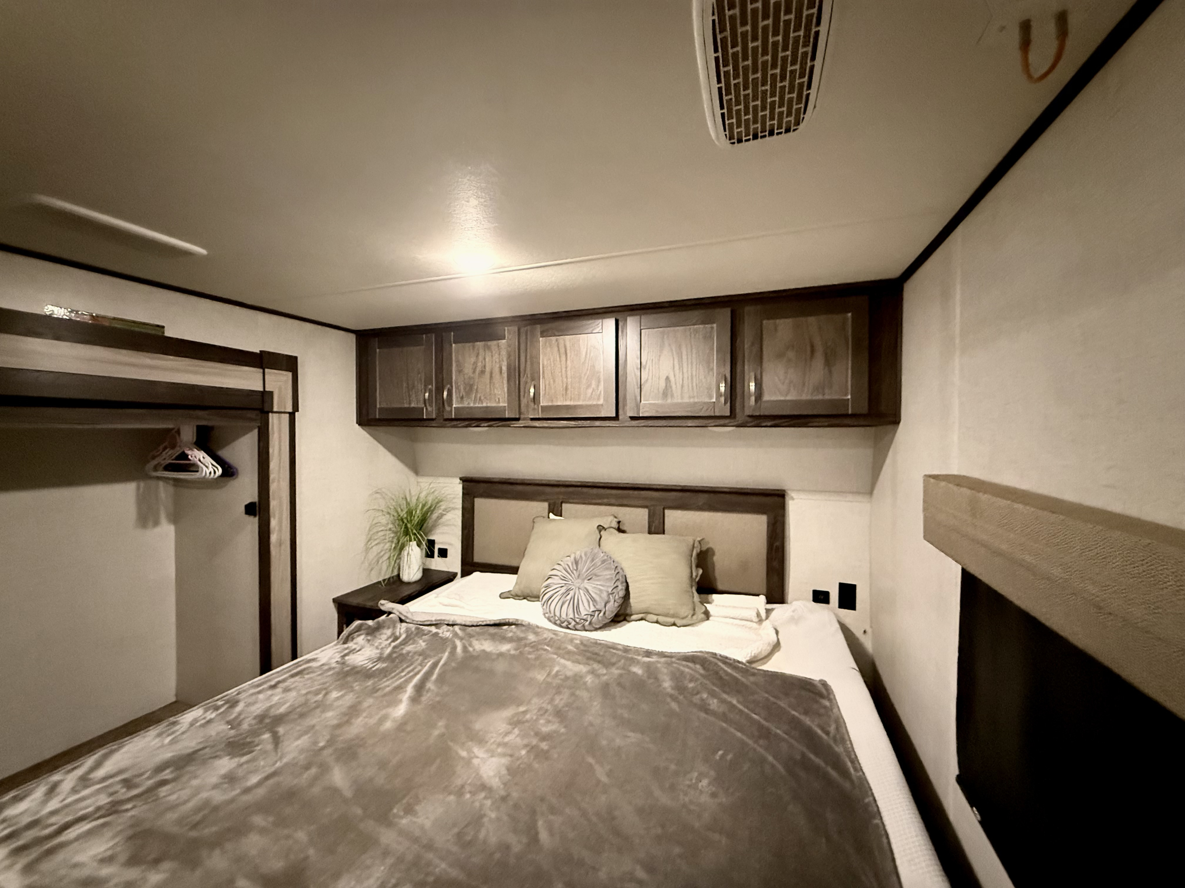 RV rental: A well-appointed bedroom with a bed, nightstand, overhead cabinets, and a small closet.. Highland Ridge RV Open Range 2021