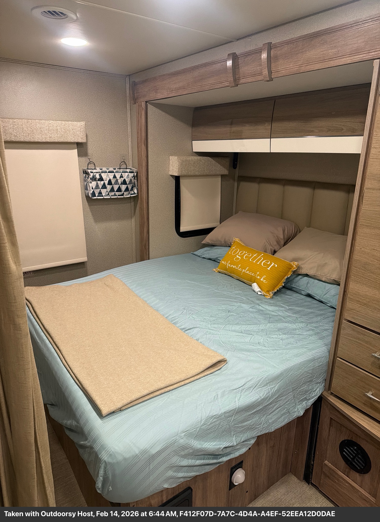 Cozy RV rental bedroom featuring a comfortable bed with a "together" pillow, convenient overhead storage, and warm lighting.. Entegra Coach Qwest 2020