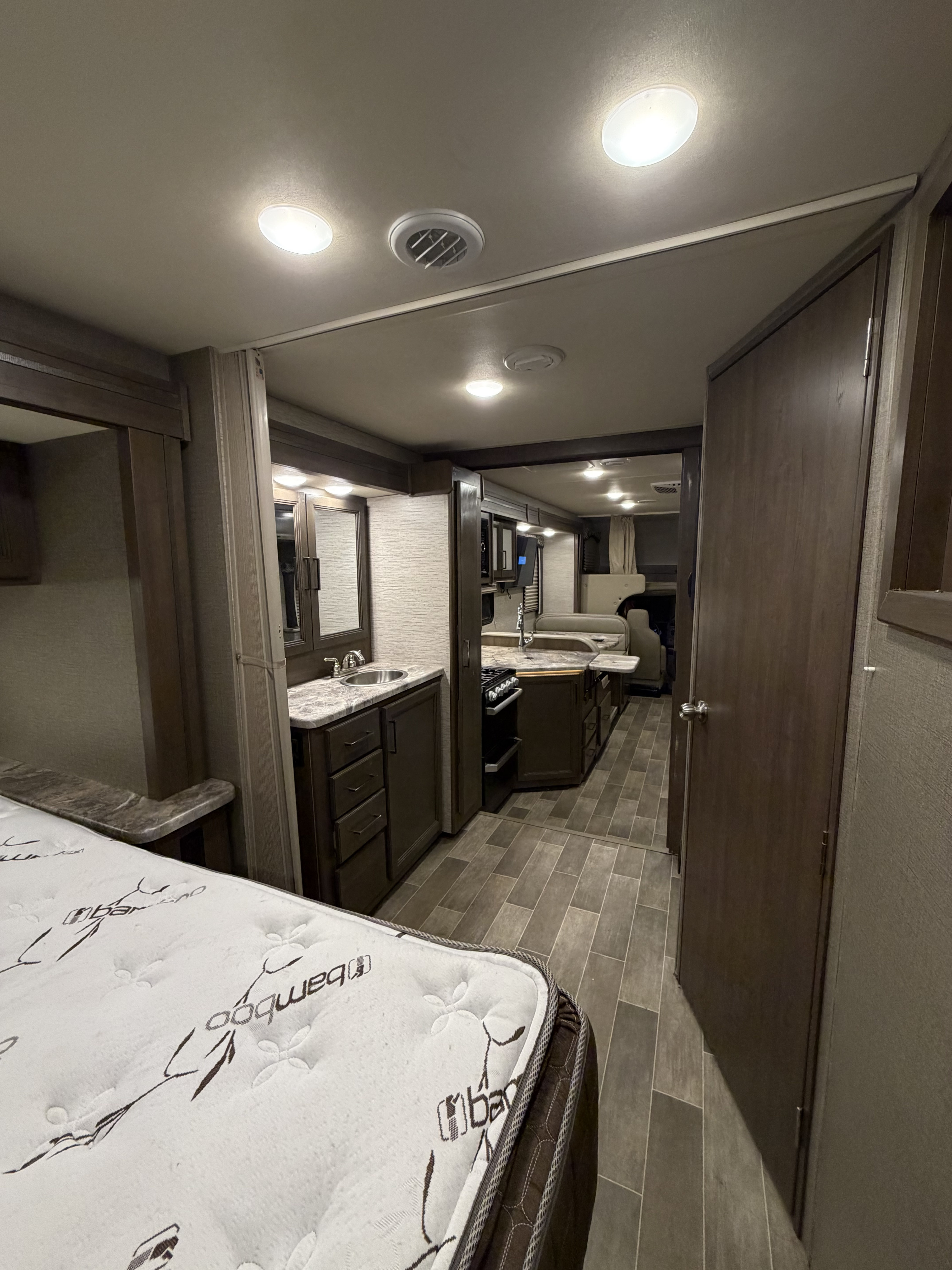 Exploring a clean RV rental's interior: comfy bedroom, well-equipped kitchen, vanity, and dining space.. Thor Chateau 2021