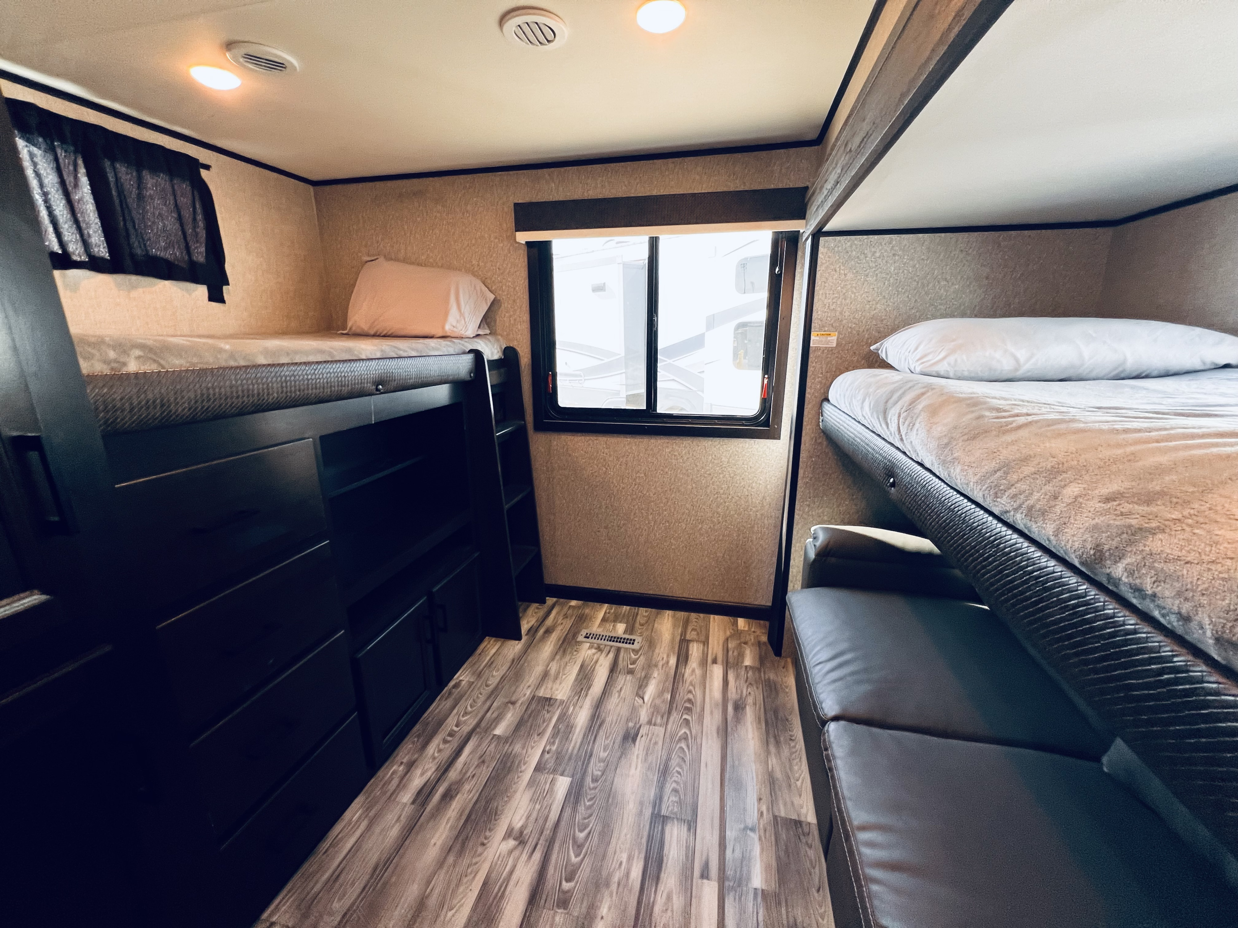 Cozy RV rental bunk bed area with integrated storage, window, and comfy seating, ideal for family travel.. Jayco Eagle 312 BHOK 2024