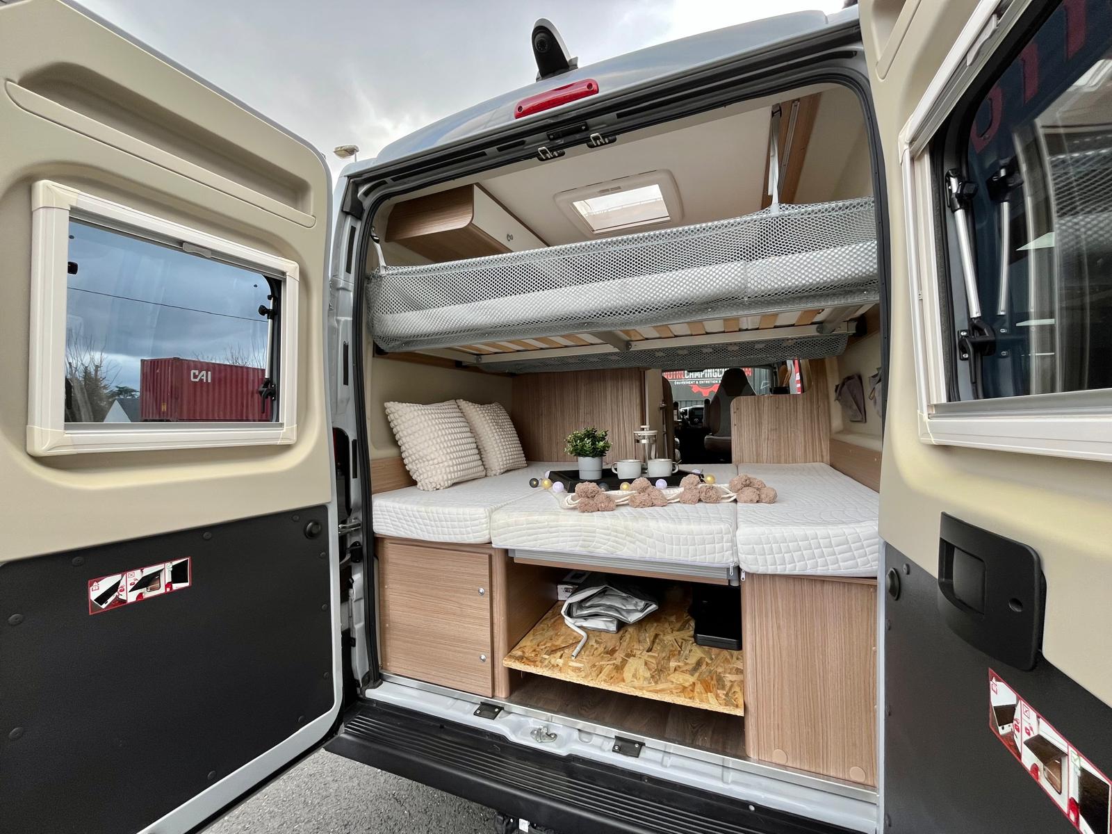 Modern camper van rv rental interior featuring comfortable bunk beds, lower sleeping area with storage, seen from rear.. CARADO CV 601 2021