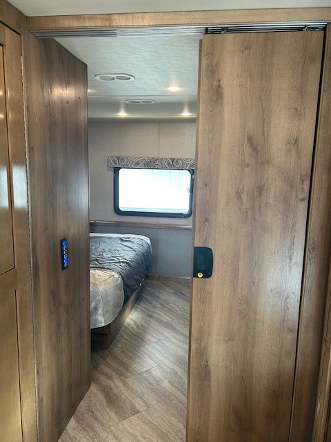 RV rental bedroom: View through open sliding doors into a modern bedroom with a bed and wood-look floor.. Bounder Bounder Motorhome 2019