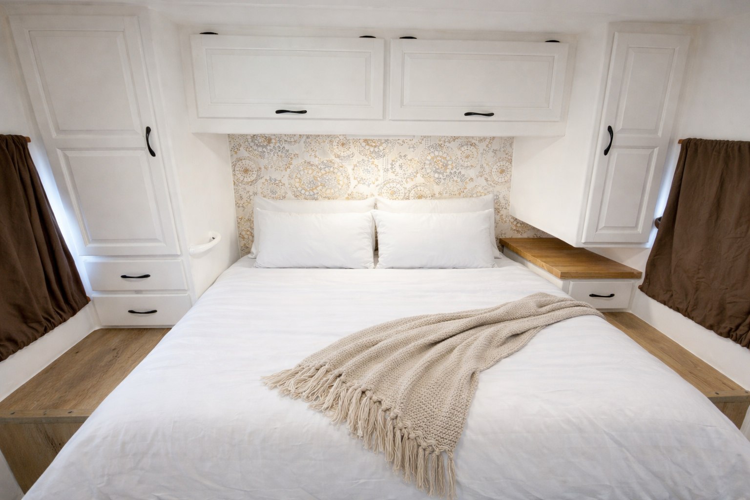 Cozy RV rental bedroom with white bedding, patterned headboard, overhead storage, and wood shelves, offering comfort on the road.. Four Winds Majestic 2011