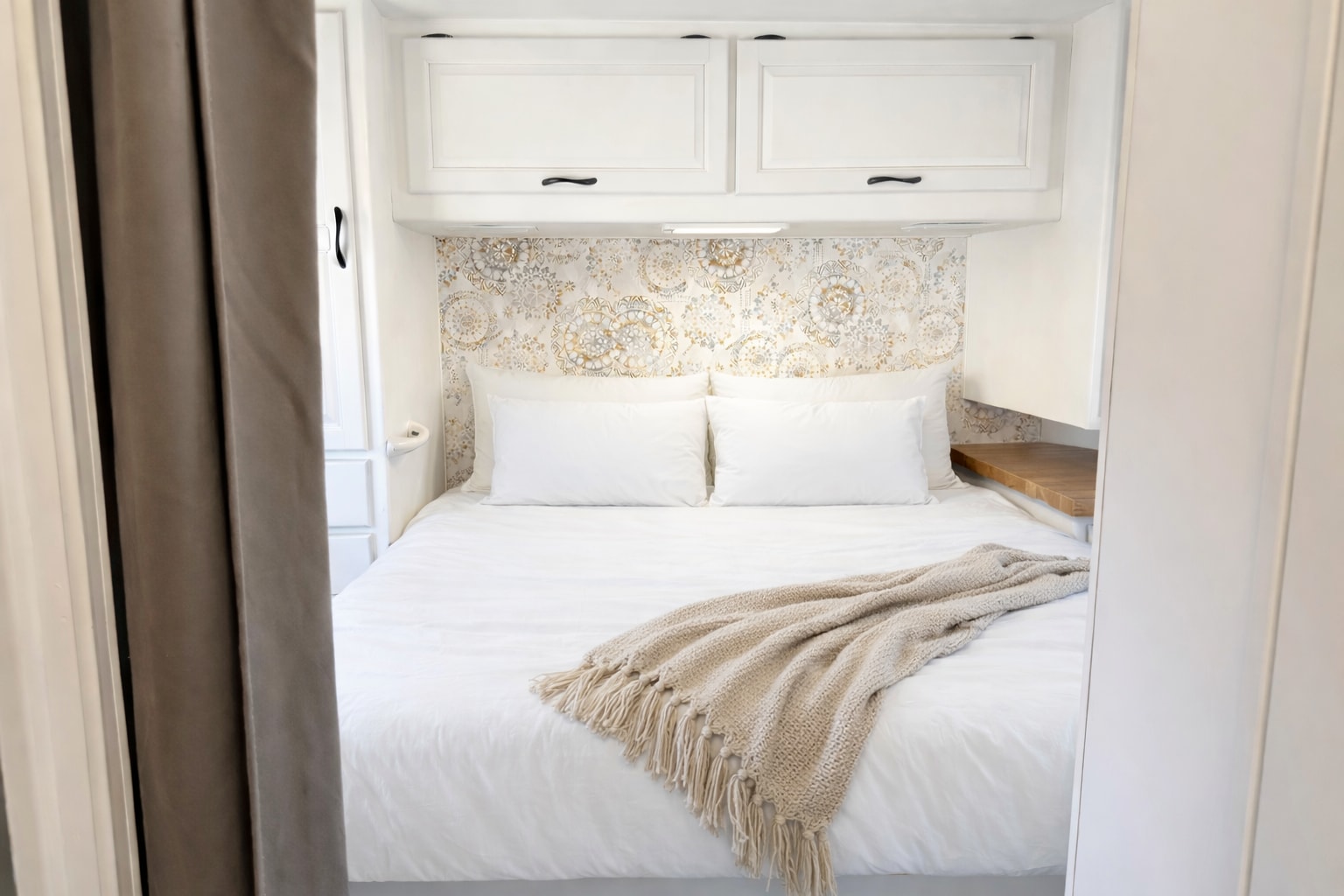 Cozy RV rental bedroom features a modern white bed, stylish patterned headboard, and functional overhead storage.. Four Winds Majestic 2011