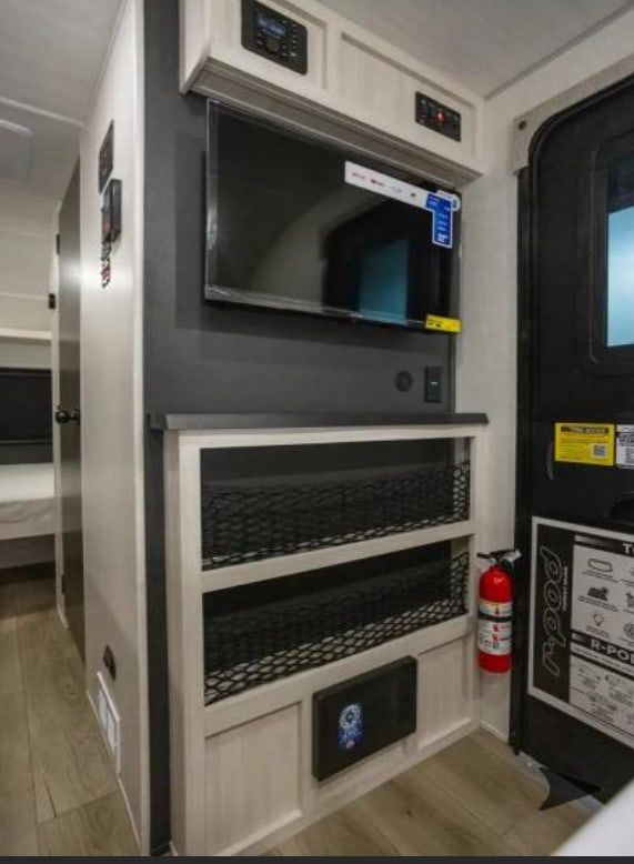 RV rental interior featuring a wall-mounted TV, built-in mesh storage, control panels, and a fire extinguisher by the door.. R-Pod R-Pod Trailer 2026