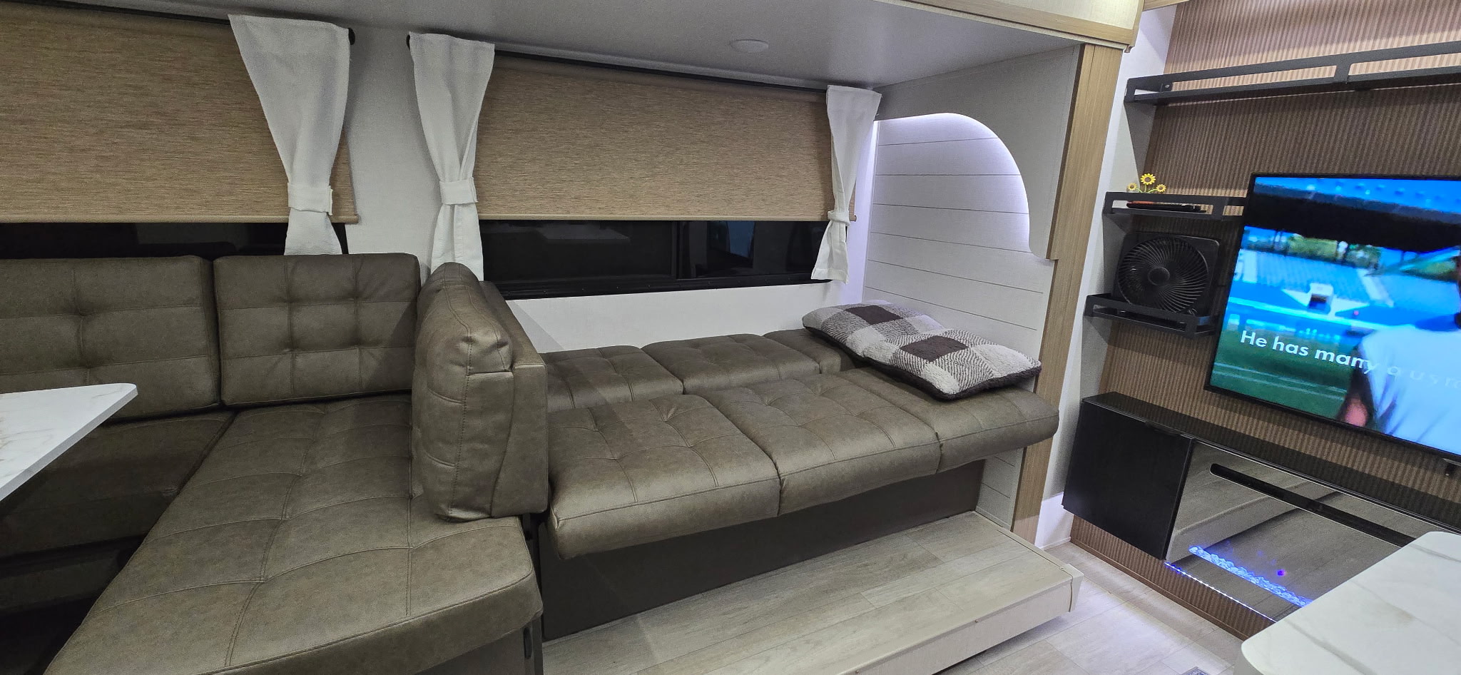 Modern rv rental living area with a cozy, convertible sectional sofa, TV, and decorative fireplace for a comfortable stay.. Forest River Wildwood X-Lite 28VBXL 2026