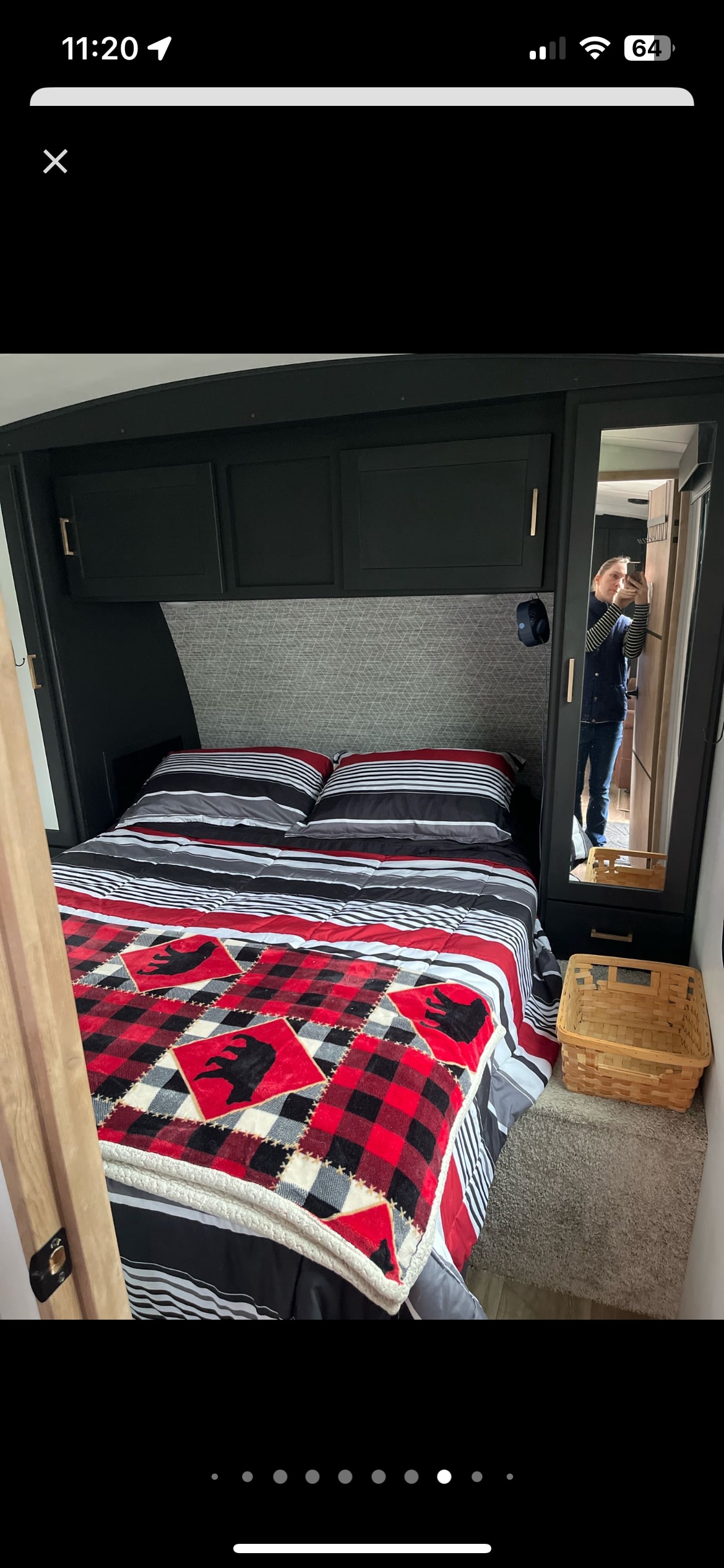 RV rental bedroom featuring a cozy plaid bear blanket, striped bedding, and dark cabinets. A mirror reflects the person taking the photo.. Keystone RV Outback 2022