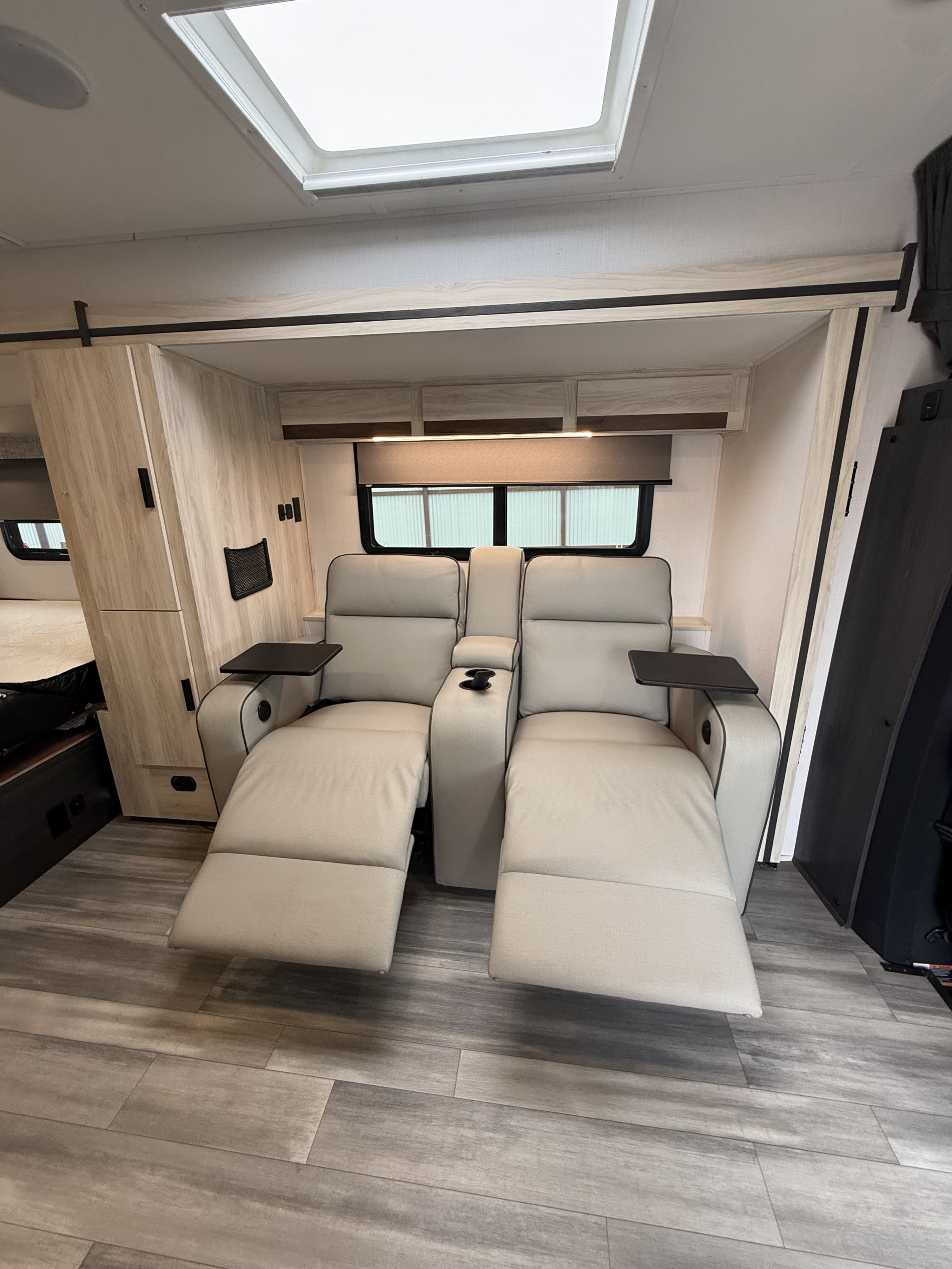 Relax in this RV rental's cozy living area. Features include two light-colored recliners with extended footrests & swivel tables.. Forest River Sunseeker MBS 2022