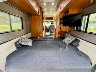 RV rental interior: A comfortable sleeping area with a large bed, pillows, TV, and windows in a compact campervan.. Roadtrek Roadtrek Class B 2016