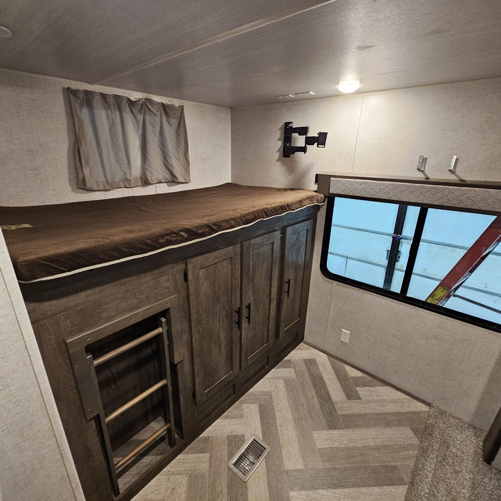 RV rental bunkhouse featuring a single bunk with brown mattress, built-in storage cabinets, a ladder, window, and TV mount.. Salem 33TS 2020