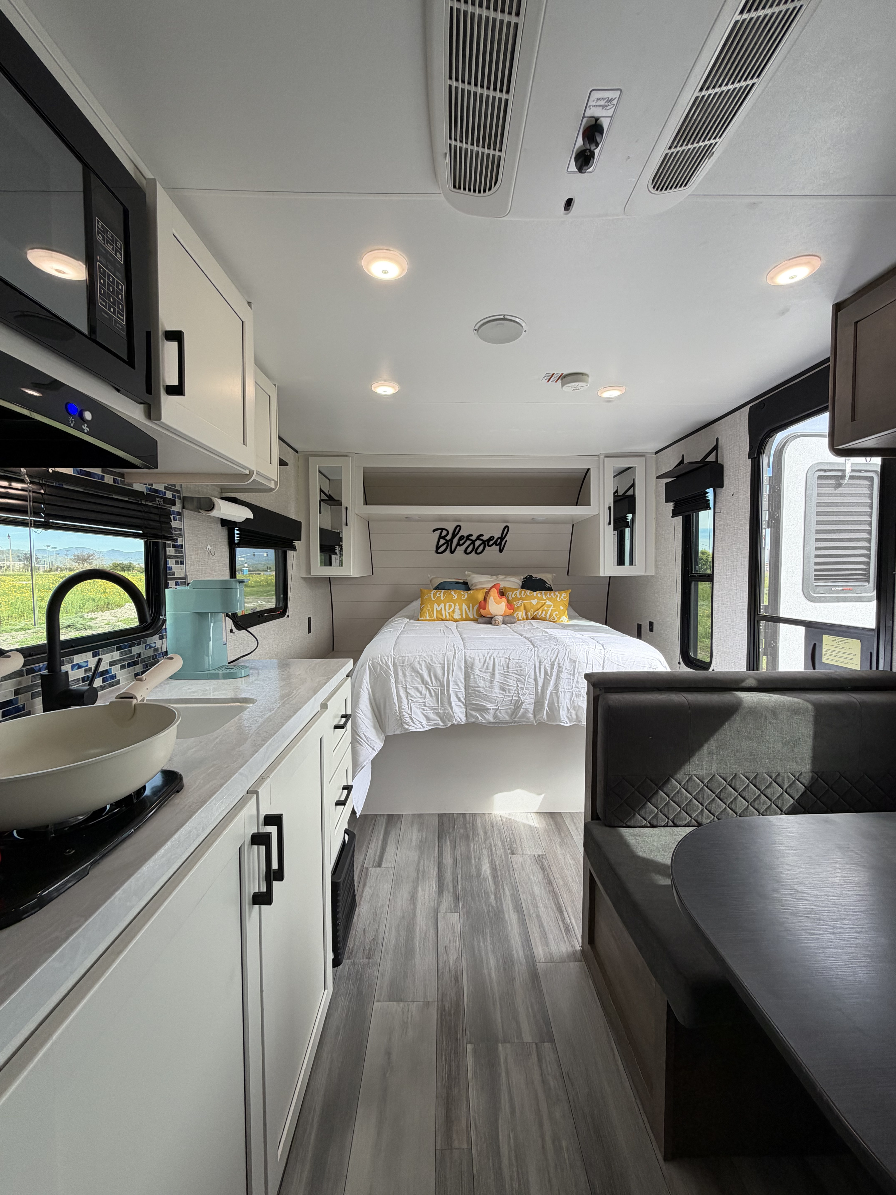 Modern RV rental interior showcasing a bright kitchen, cozy bed with decorative pillows, and a comfortable dinette.. Jayco Jay Flight SLX Baja Edition 2025