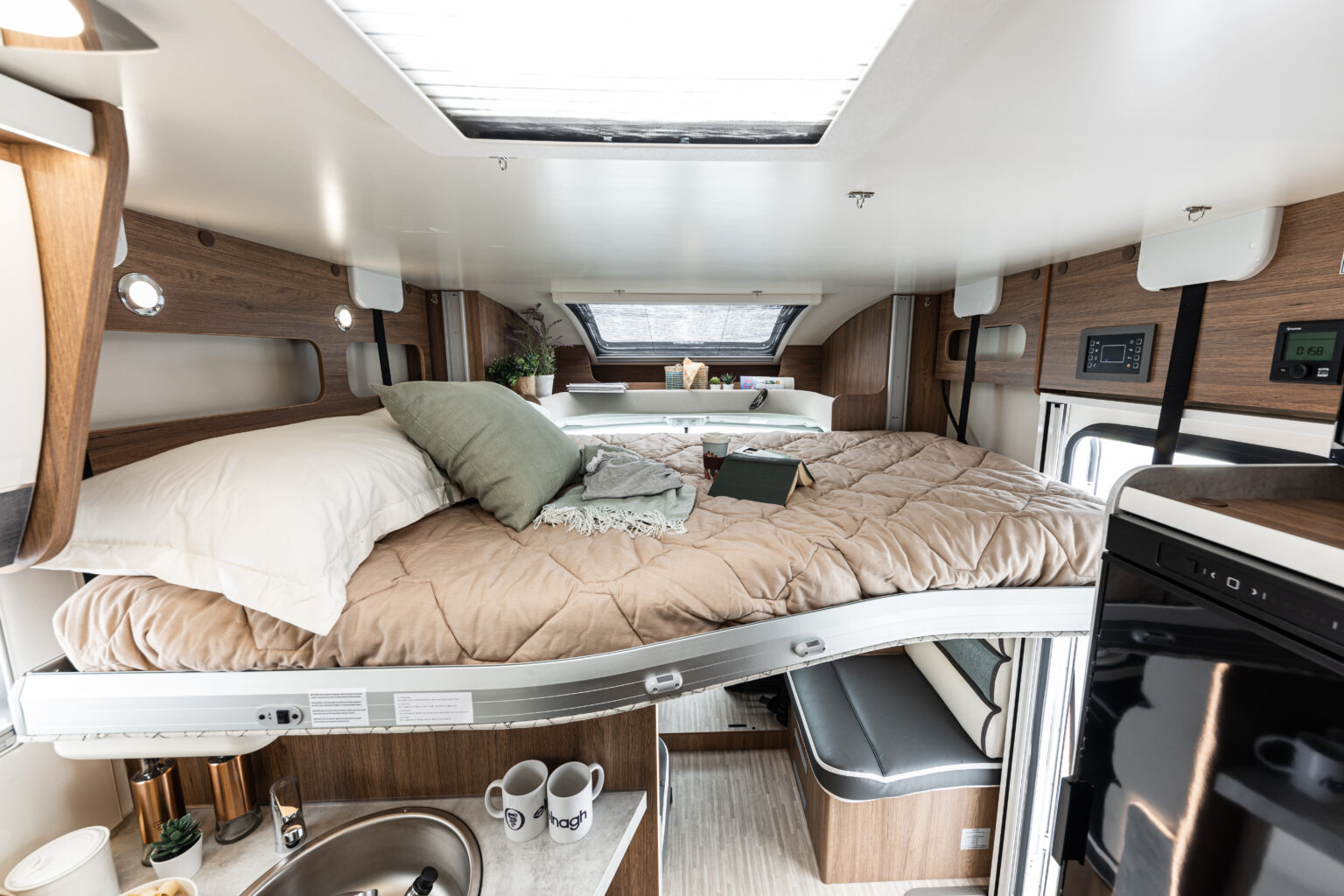 Cozy rv rental interior featuring a large bed, complete with kitchen sink and a small seating area below for convenient mobile living.. ELNAGH BARON 573 2026