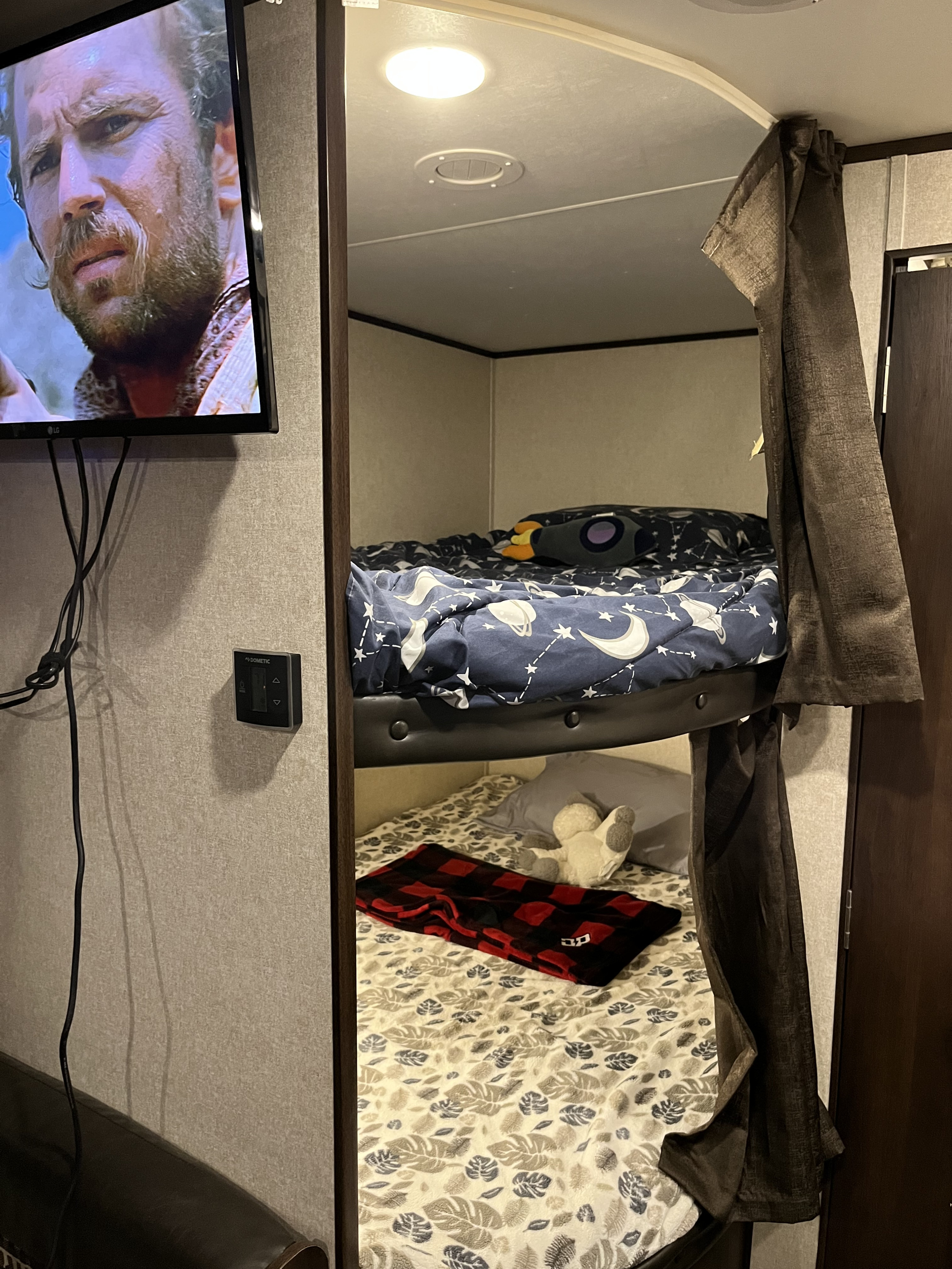 RV rental bunk beds: top with space bedding & rocket pillow, lower with plaid blanket & toy. TV on left wall. Ideal camper sleeping.. Jayco Jay Flight SLX 2018