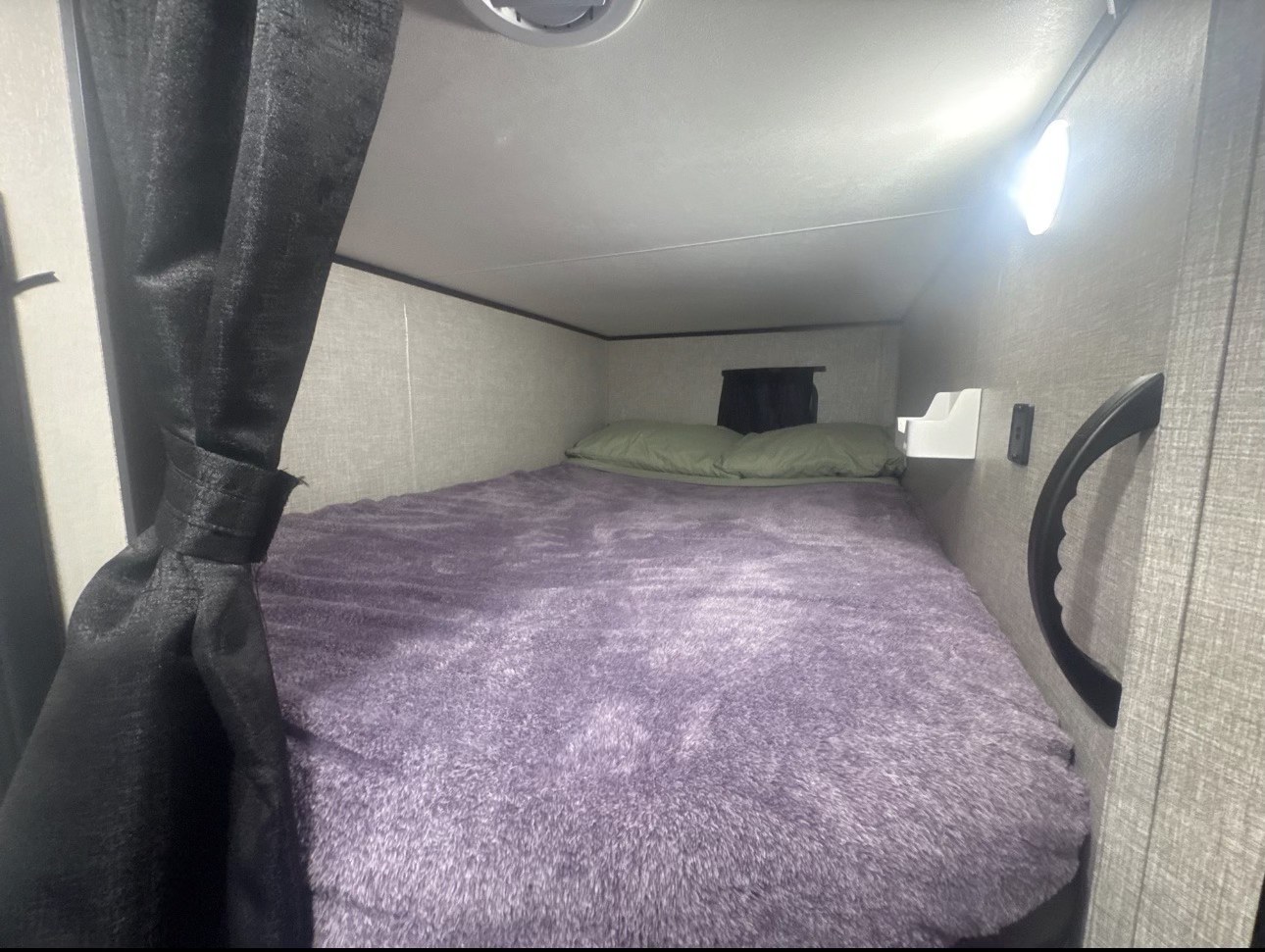 Cozy RV rental bunk bed featuring a plush purple blanket, light, and convenient storage for a comfortable journey.. Jayco Jay Flight SLX 2021