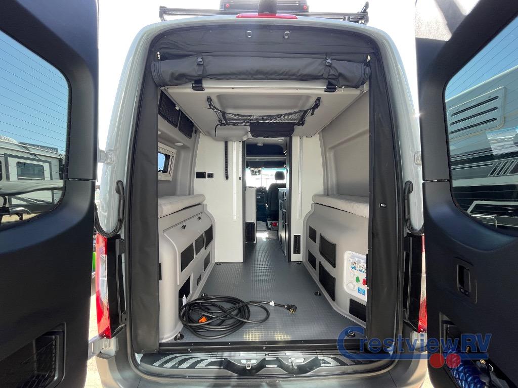 Rear view of an rv rental camper van, doors open to reveal its modular interior with benches, durable flooring, and a power cord.. Winnebago Revel 2026