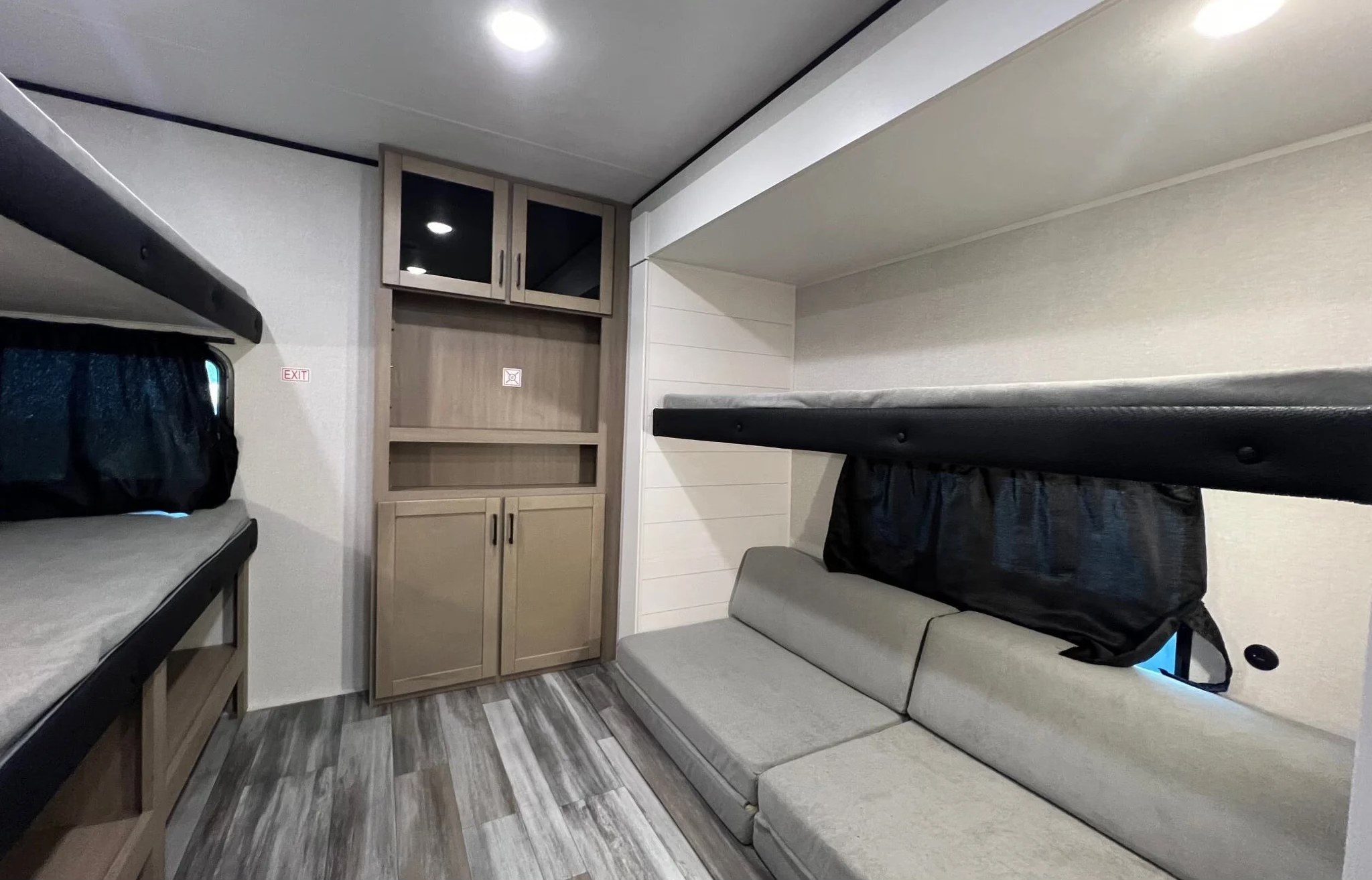 Modern RV rental bunkhouse with two bunk beds, a gray sofa, and wood-look cabinetry. Light wood-style flooring completes the interior.. Jayco Jay Flight SLX 2026
