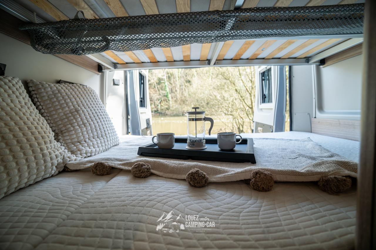 Wake up to a scenic view from your rv rental camper van. A cozy bed with a French press and mugs on a tray awaits.. CARADO CV 601 2021