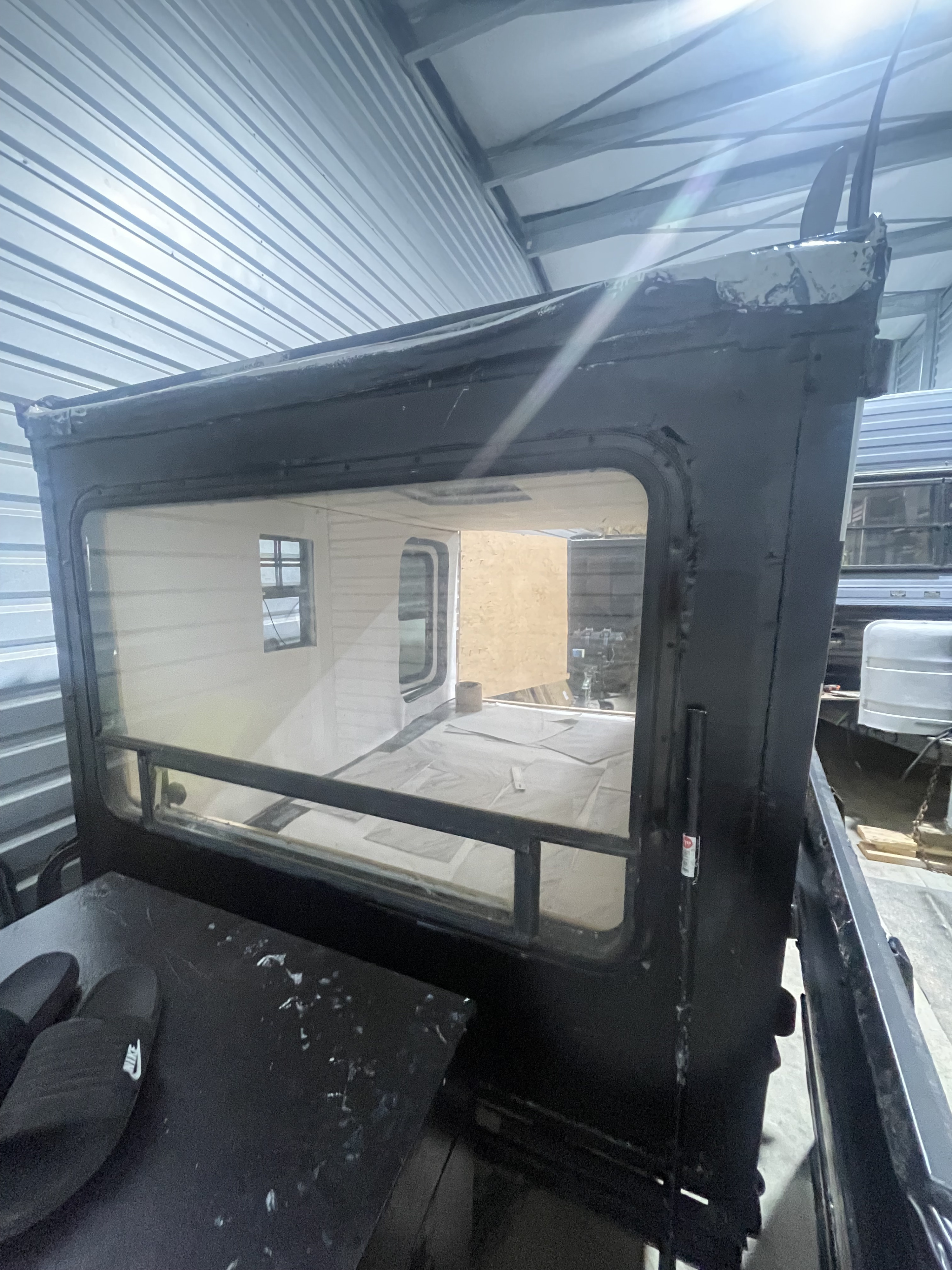 Viewing an rv rental camper's interior through a large window, showing a sleeping area, with black slides in the foreground.. Camping Equipment Cargo Trailer Conversion 2020