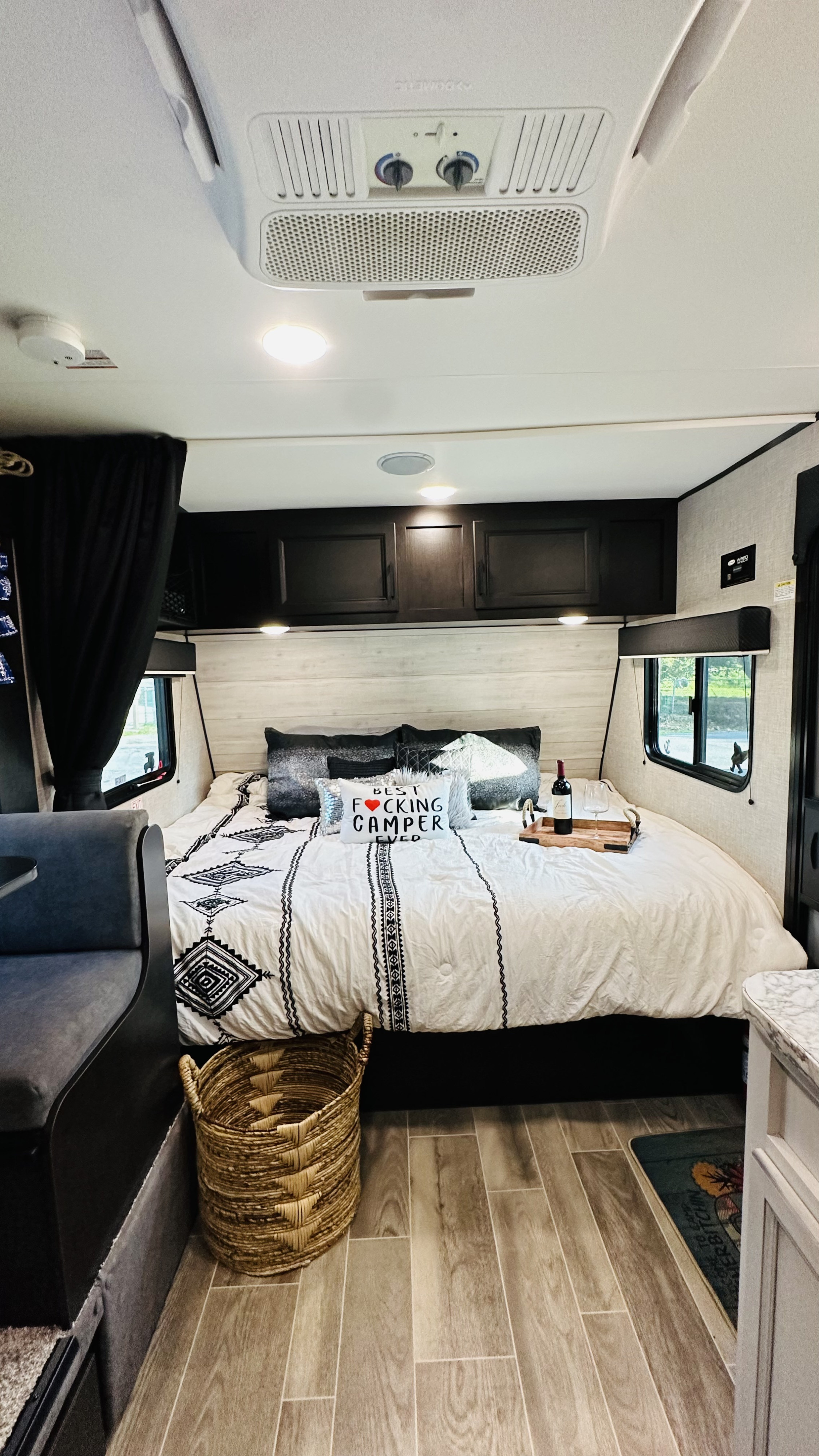 Relaxing RV rental bedroom: comfy bed, patterned duvet, wine, woven basket, and modern finishes. Your ultimate camper retreat.. Jayco Jay Flight SLX 2022