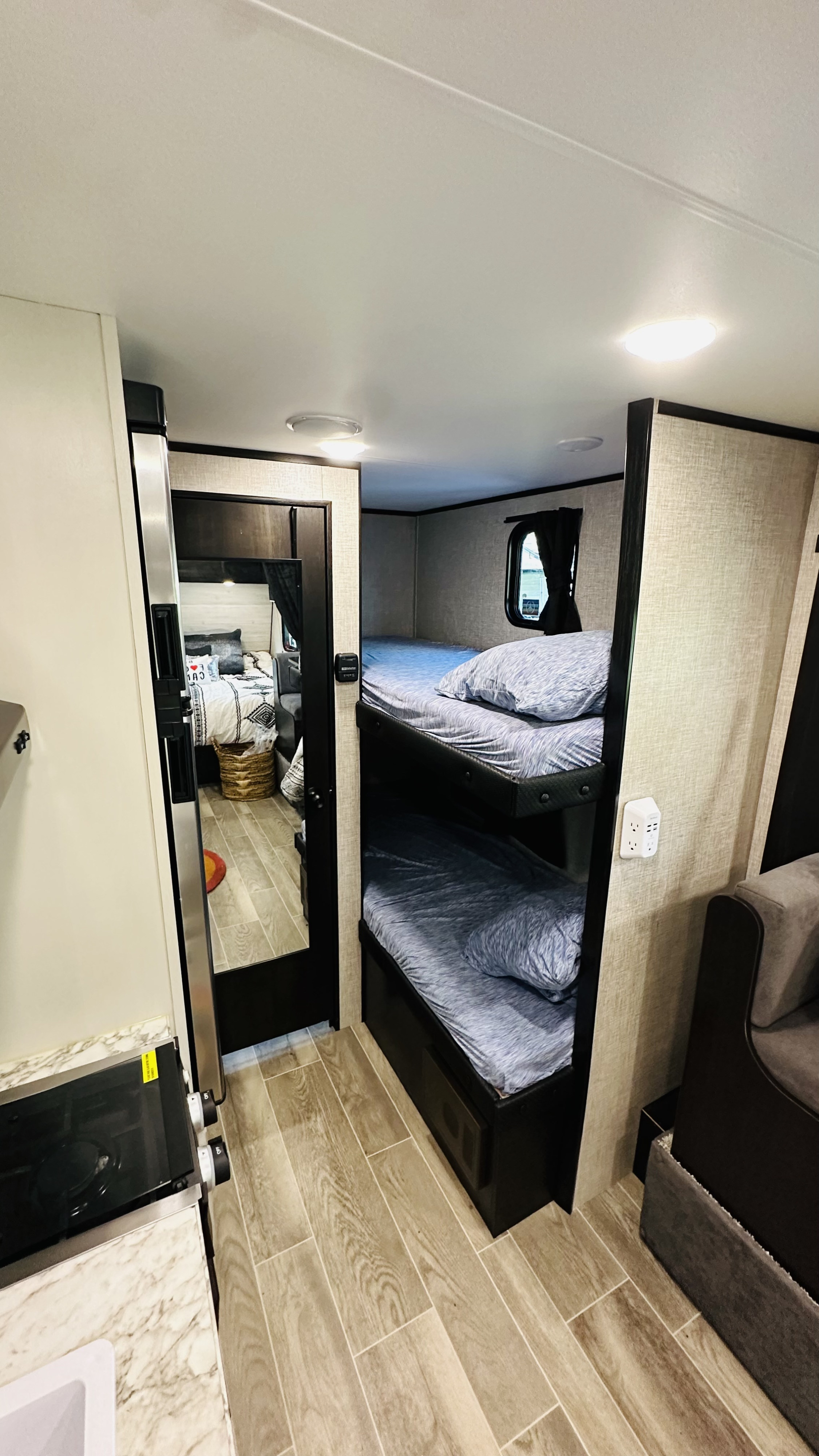 RV rental interior with bunk beds on the right, a kitchen area on the left, and a mirrored view of a bedroom.. Jayco Jay Flight SLX 2022