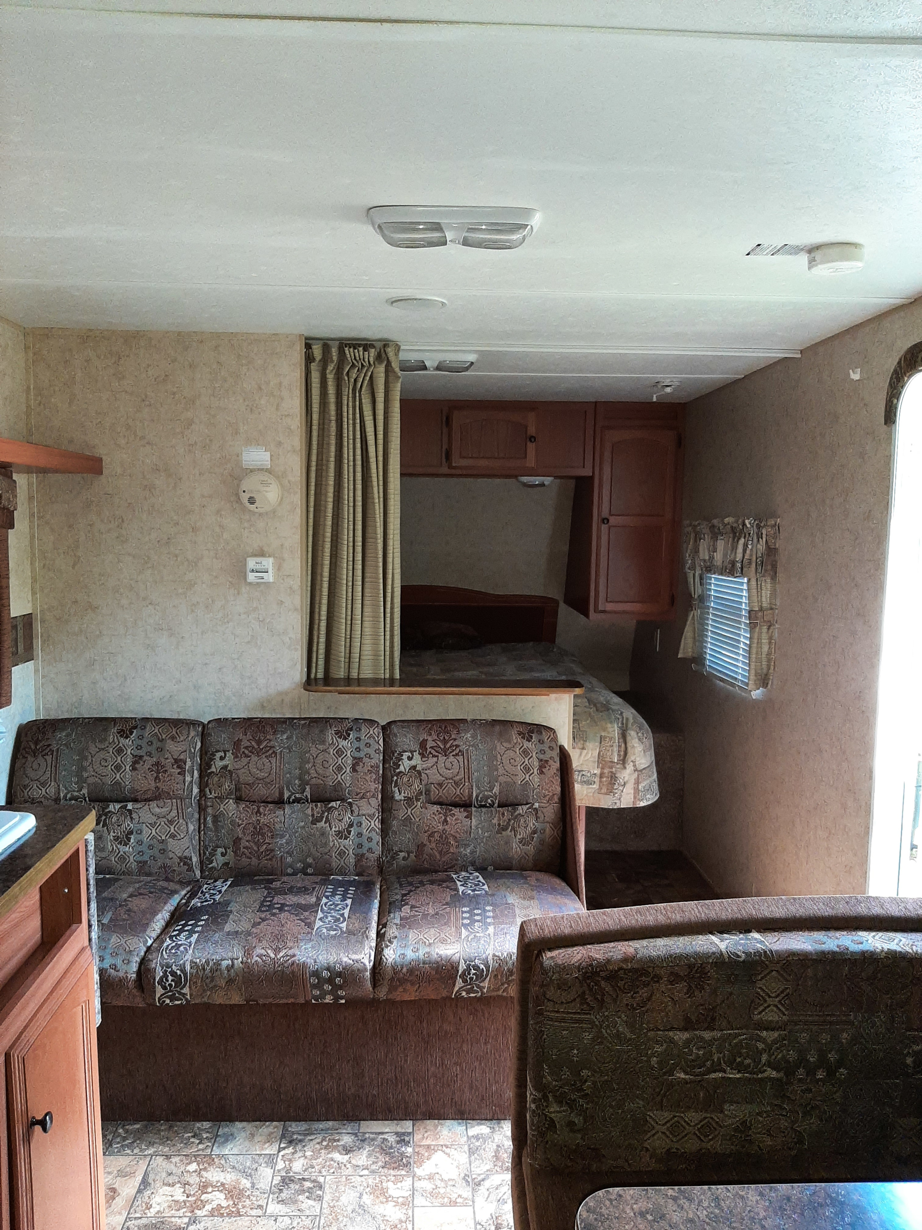 Inside this RV rental: A comfortable living area with a patterned couch, a rear bunk bed, and overhead storage cabinets.. Four Winds Breeze SS 2010