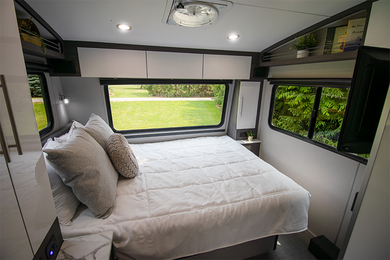 Comfortable RV rental bedroom with a spacious bed, bright windows, and convenient overhead storage. Enjoy the view!. InTech RV Aucta Magnolia 2024