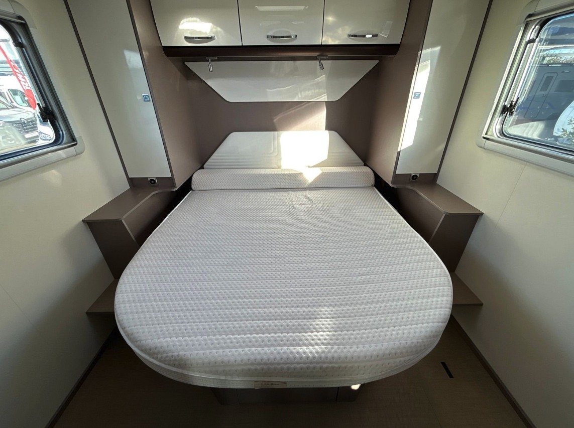 A bright, spacious bed with overhead cabinets and side storage in a modern rv rental, ready for comfortable camper journeys.. BURSTNER Lyséo TD 736 Privilège 2023